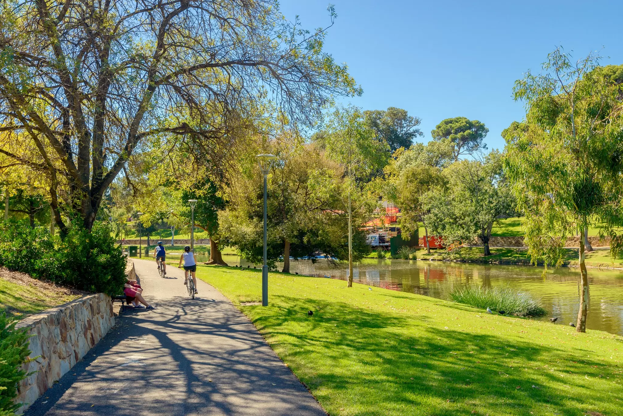 Unrecognized people riding their bicycles along Torrens river bike track in North Adelaide on a bright day