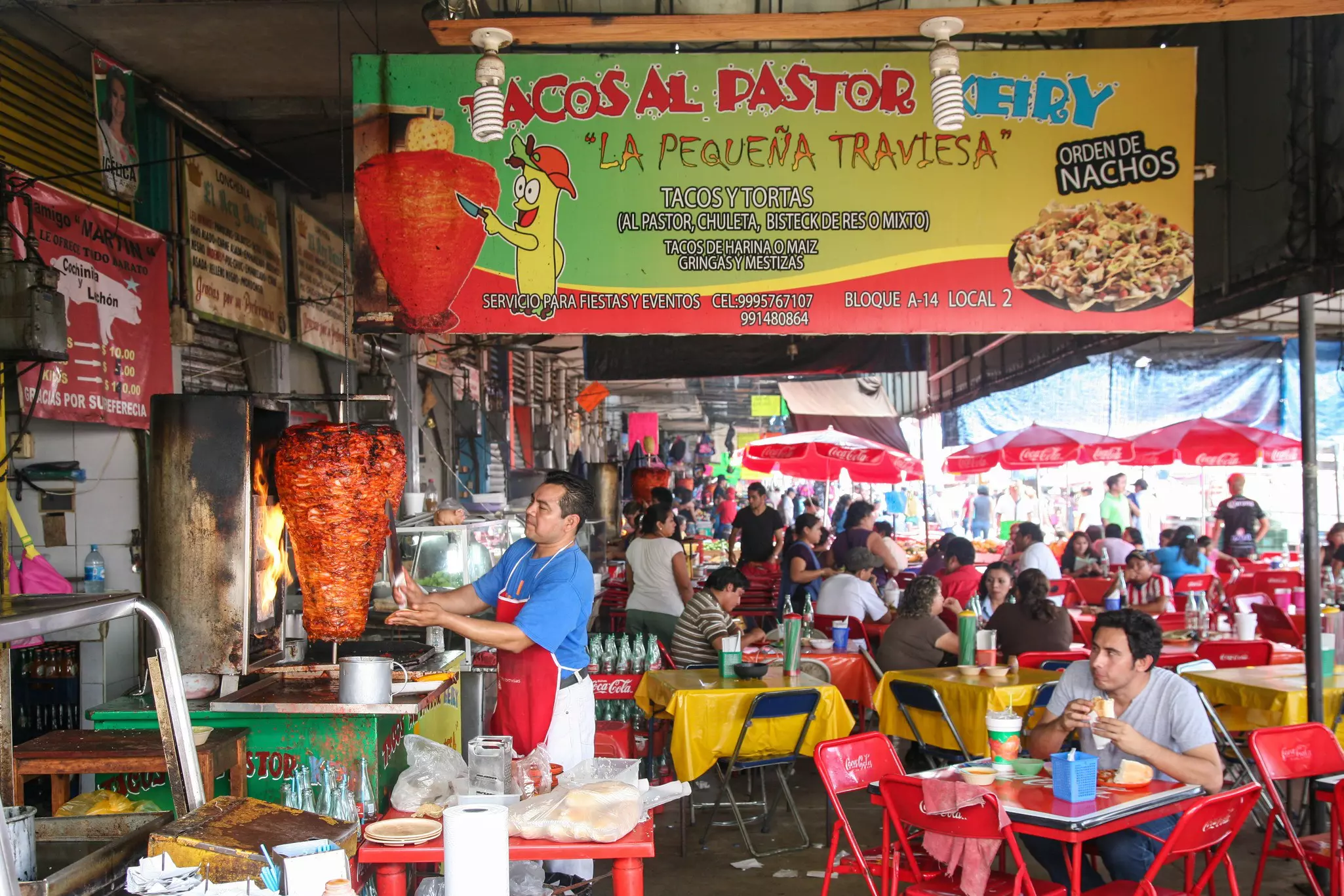 A man carves meat for tacos al pastor among crowded tables at the Mercado Municipal Lucas de Gálvez market in Mérida, Mexico