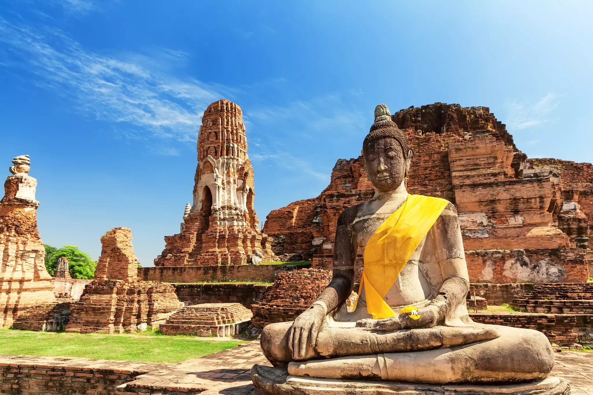 A statue of Buddha in front of the ruins of a temple.