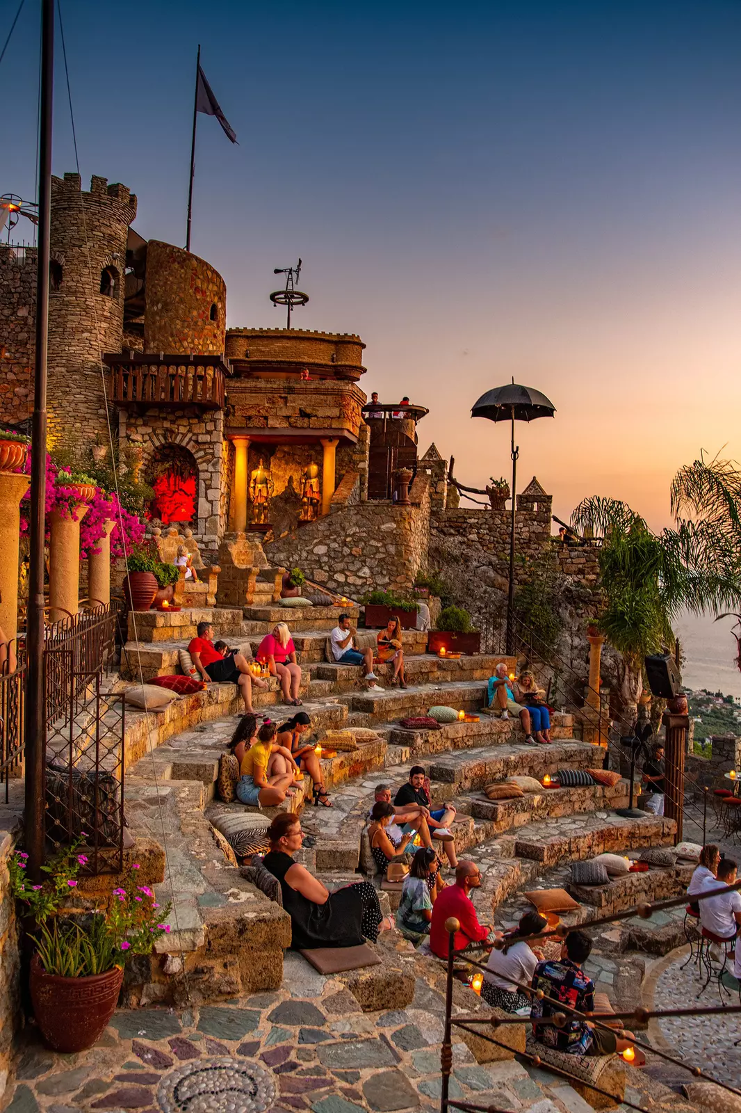 People sit in arena-style seating at a cafe bar during sunset