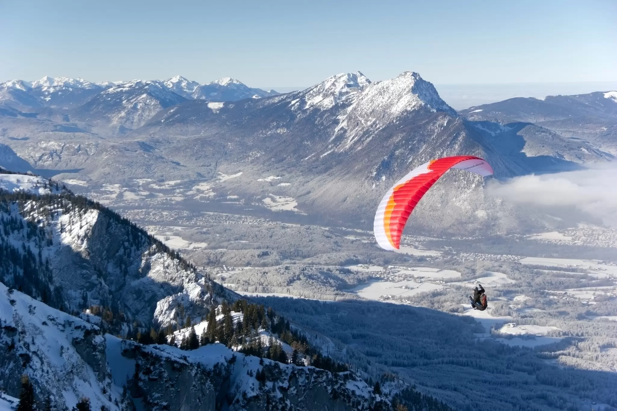 A paraglider flying over a winter landscape after starting in Untersberg, Salzburg. Barbara Lechner/Shutterstock