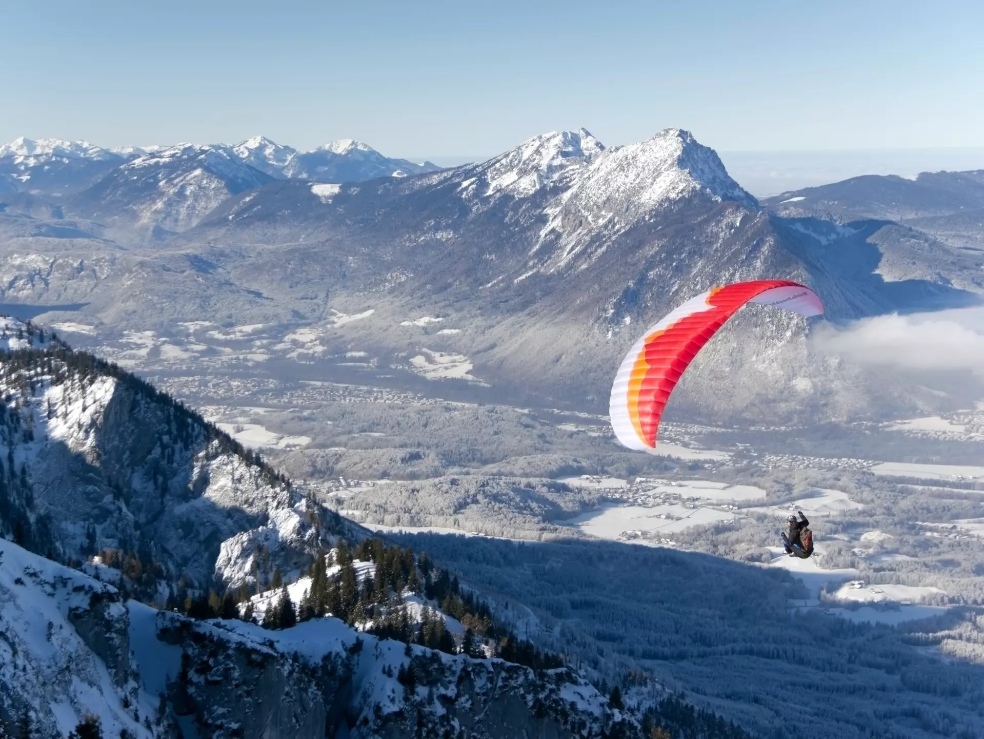 A paraglider flying over a winter landscape after starting in Untersberg, Salzburg. Barbara Lechner/Shutterstock