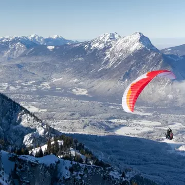 A paraglider flying over a winter landscape after starting in Untersberg, Salzburg. Barbara Lechner/Shutterstock