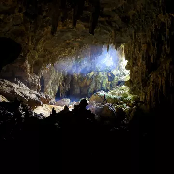 A caver stands near the entrance of Tu Lan Caves.