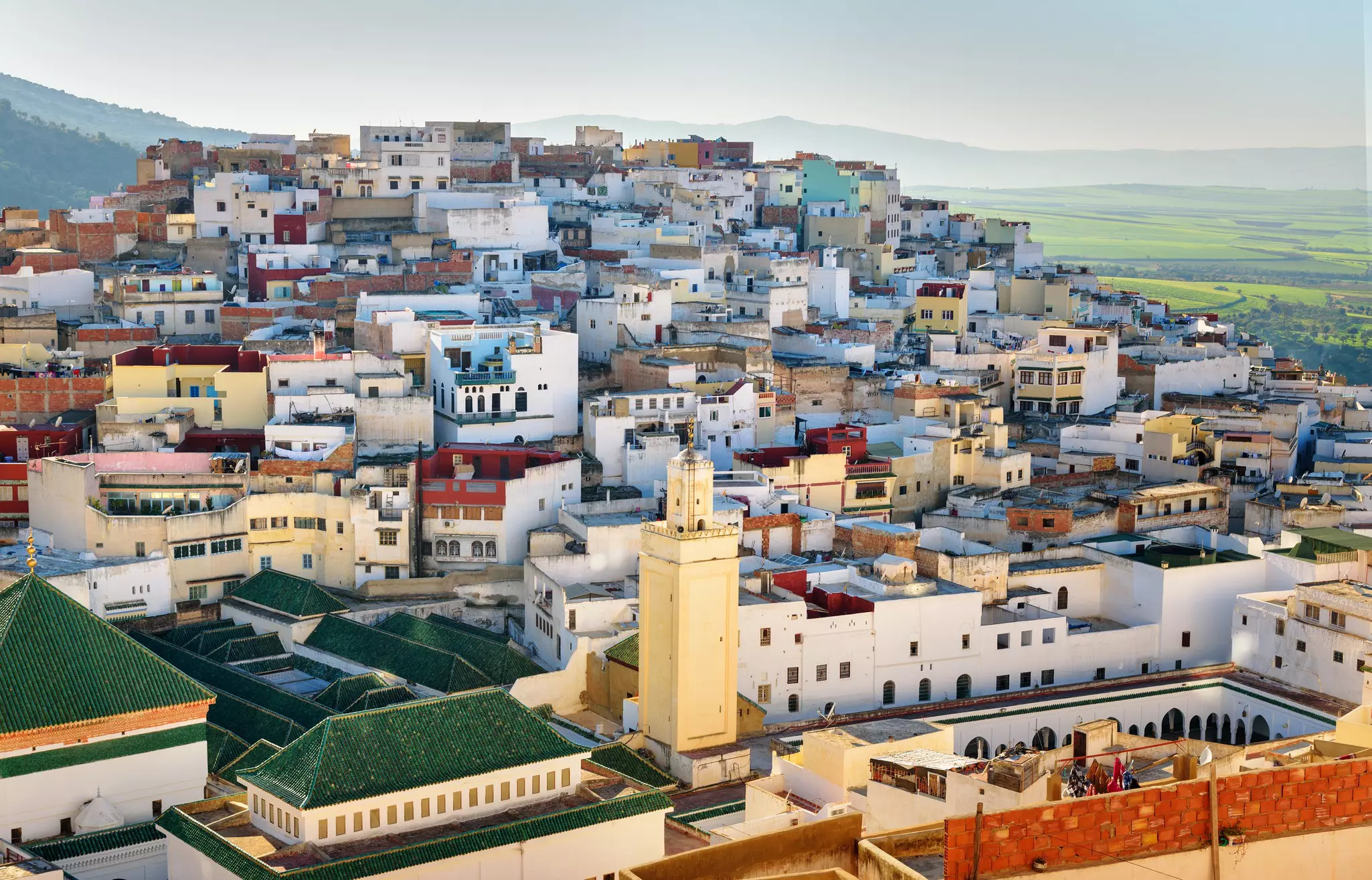 Multiple multi-colored homes on a hilltop with mountains in the background