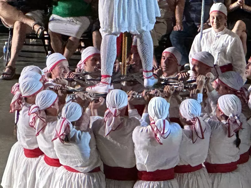 Dancer standing on a platform of swords created by the other dancers