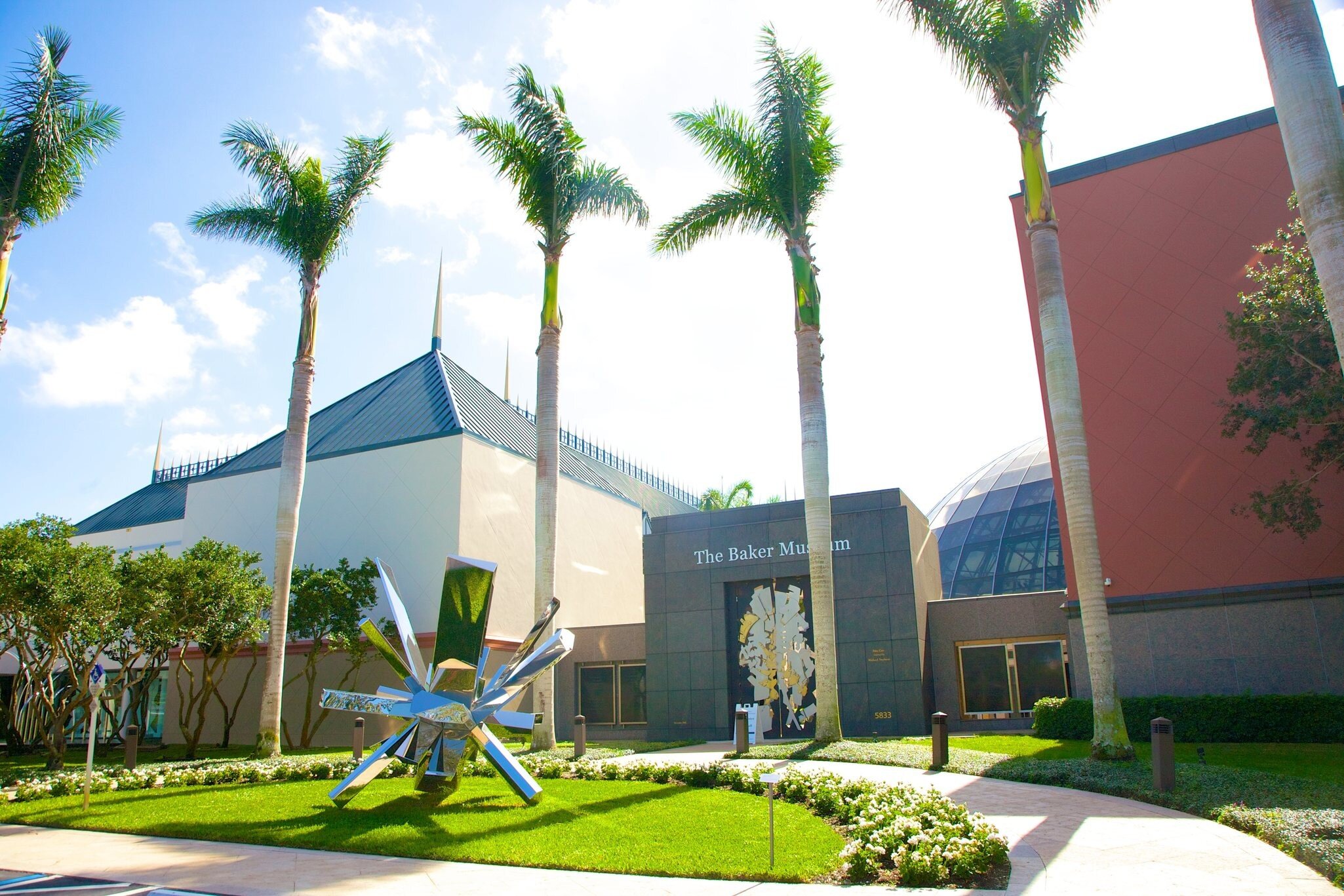 Stainless steel sculpture by artist Arik Levy titled RockGrowth 370, from 2017, in front of palm trees and main entrance to The Baker Museum, a modern art museum in Naples, Collier County, Florida, USA.  The museum houses a diverse collection of a...
