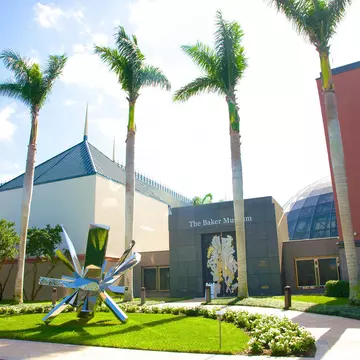 Stainless steel sculpture by artist Arik Levy titled RockGrowth 370, from 2017, in front of palm trees and main entrance to The Baker Museum, a modern art museum in Naples, Collier County, Florida, USA.  The museum houses a diverse collection of a...