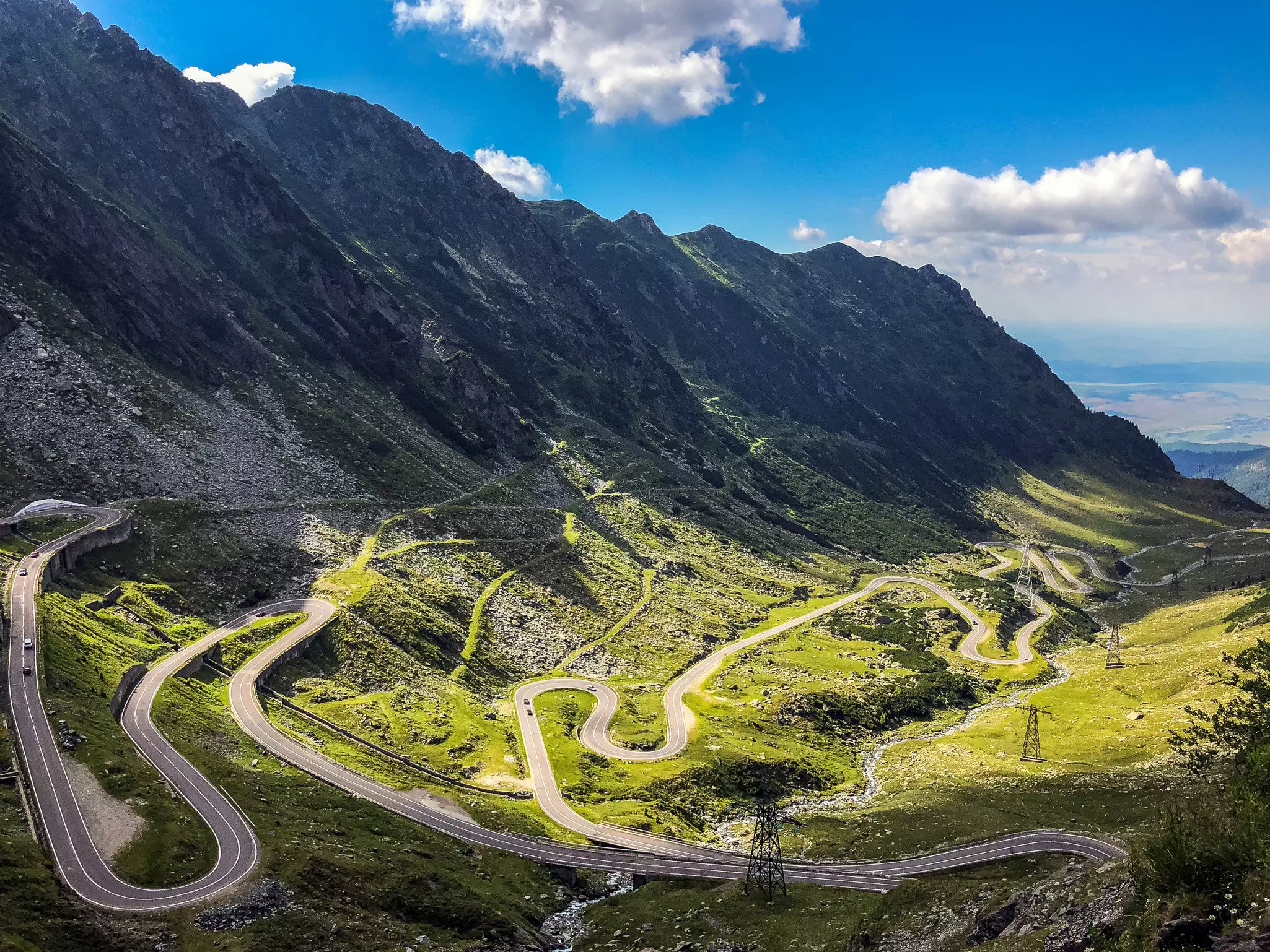 A road winds with tight hairpin bends through a mountain valley.