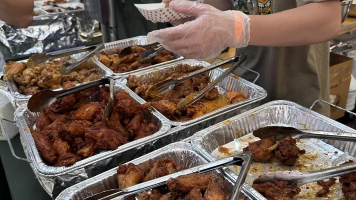 Small plate of two wings and trays of wings of different flavors behind them. 