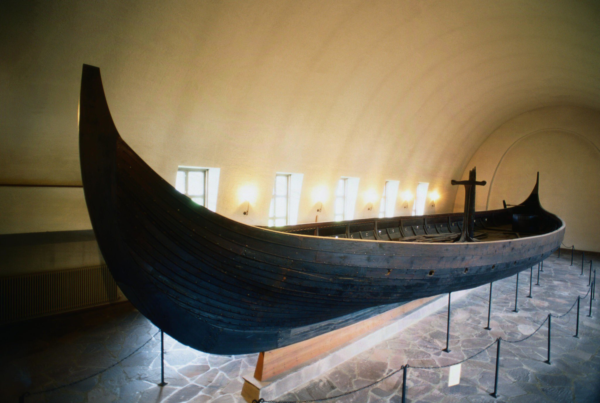 A clinker-built Viking longship on a cradle beneath a white barrel-vaulted ceiling
