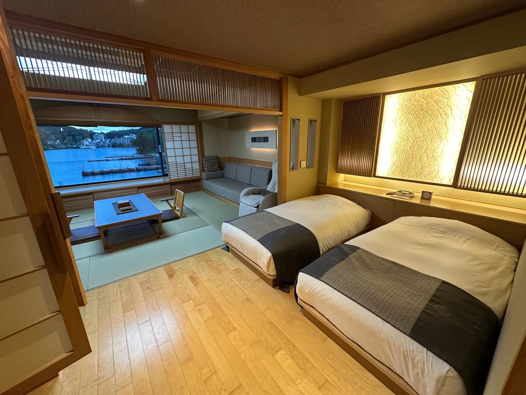 A minimalist hotel room with twin beds next to an open seating area.