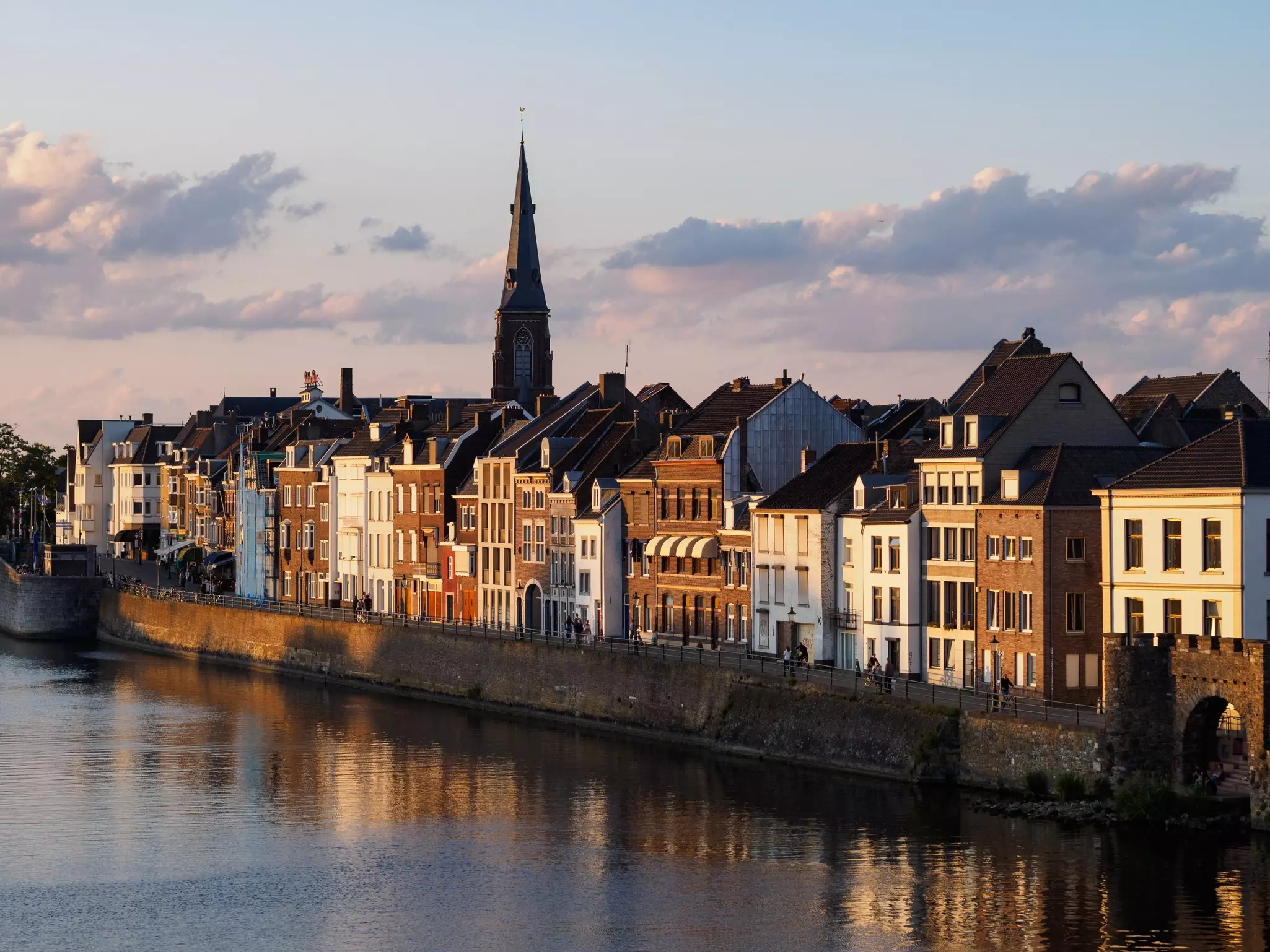 Low-rise Dutch apartment buildings overlook a canal at dusk.