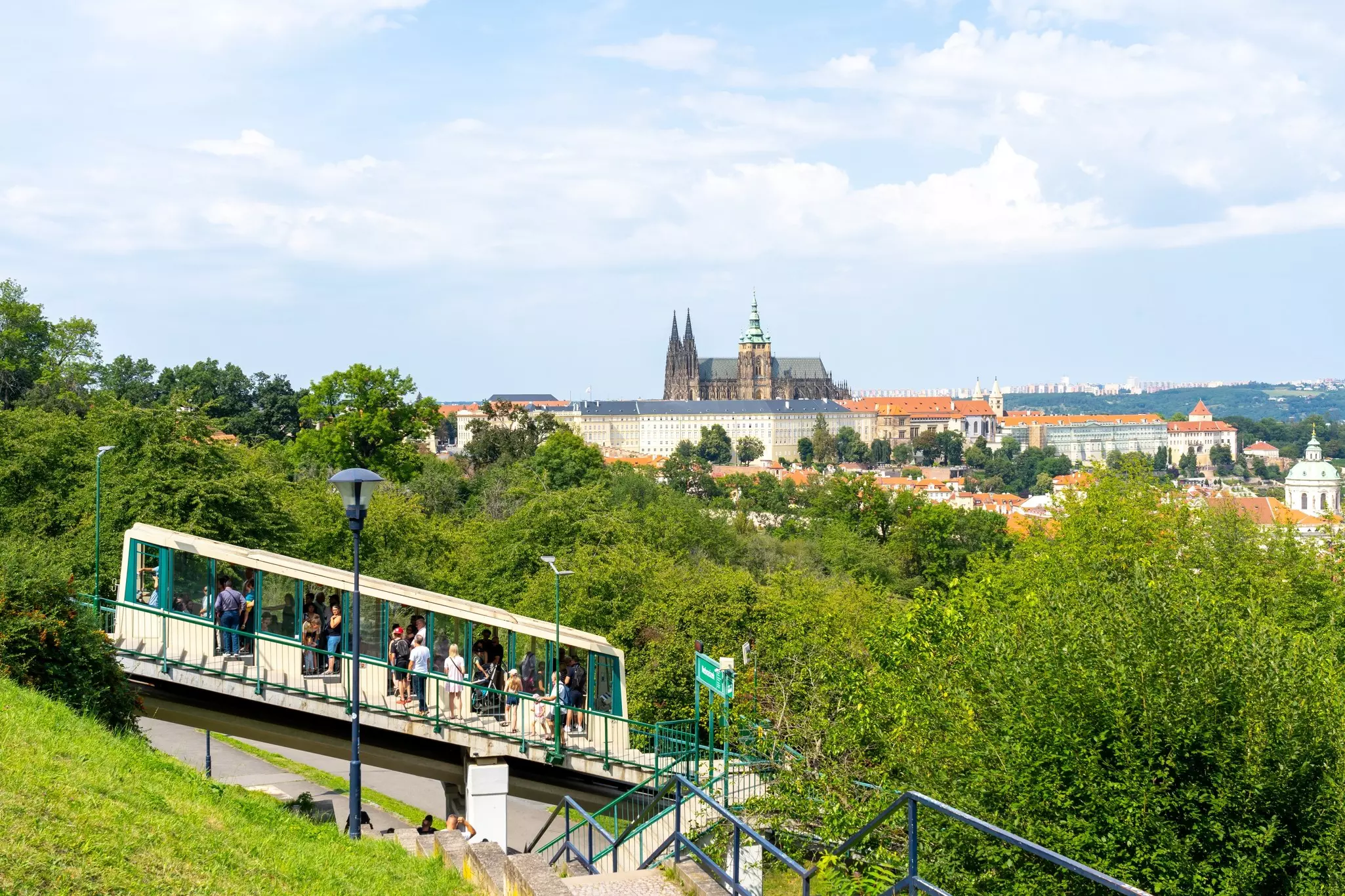 A green and white funicular on a steep climb up a hill