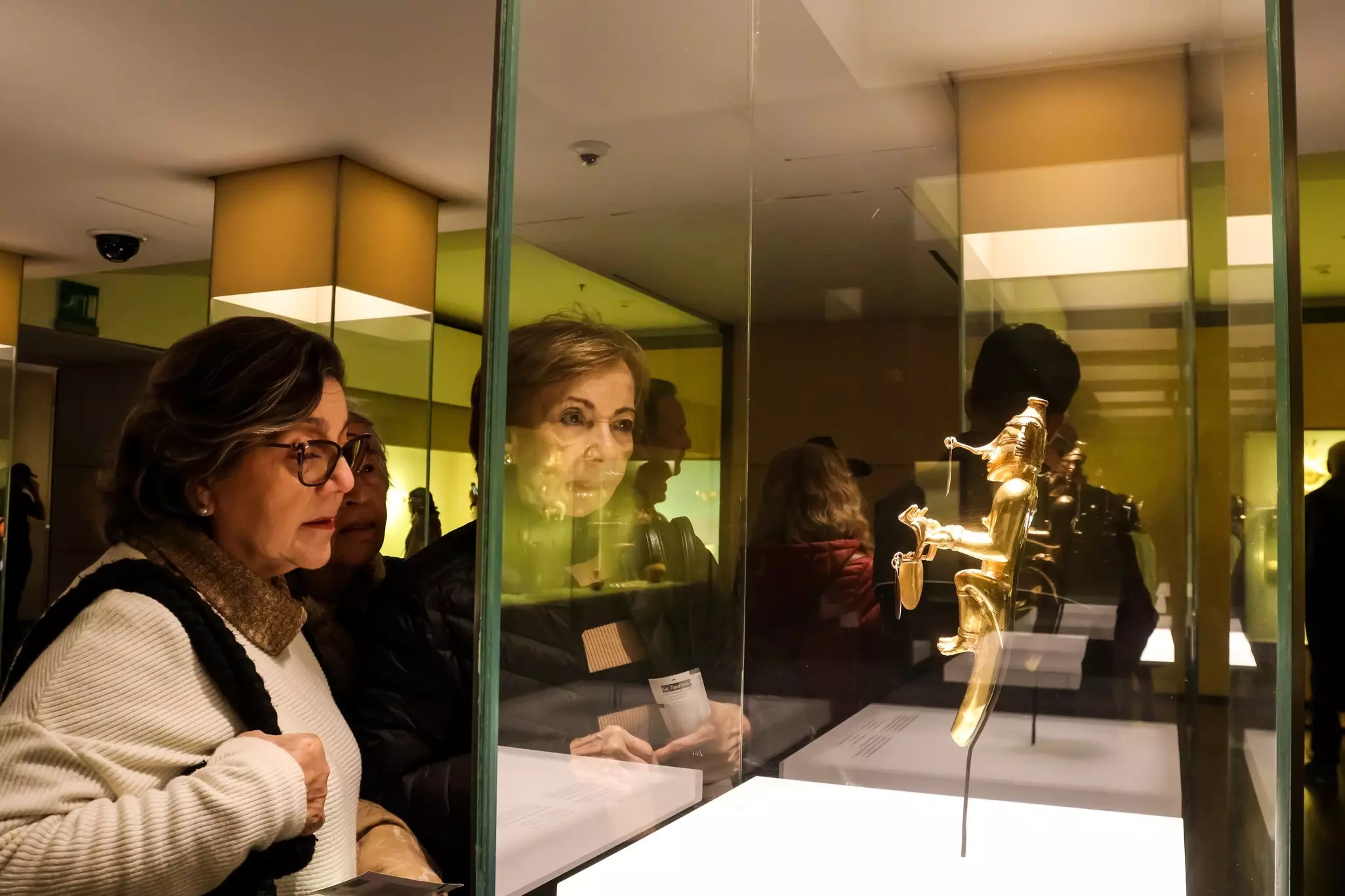 People look at a gold object in a glass case.