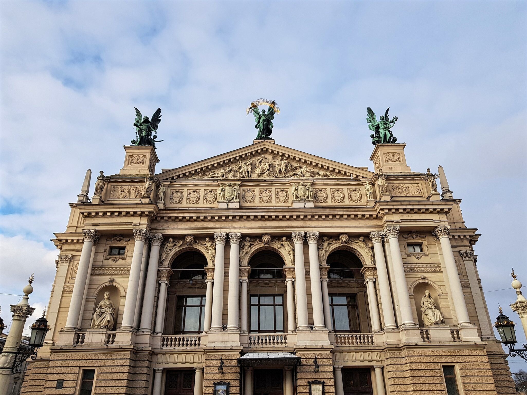 Lviv, Ukraine: cream columned opera house facade with niche statues and three green bronze winged figures on the roof