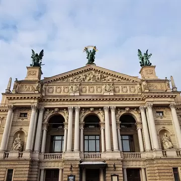 Lviv, Ukraine: cream columned opera house facade with niche statues and three green bronze winged figures on the roof