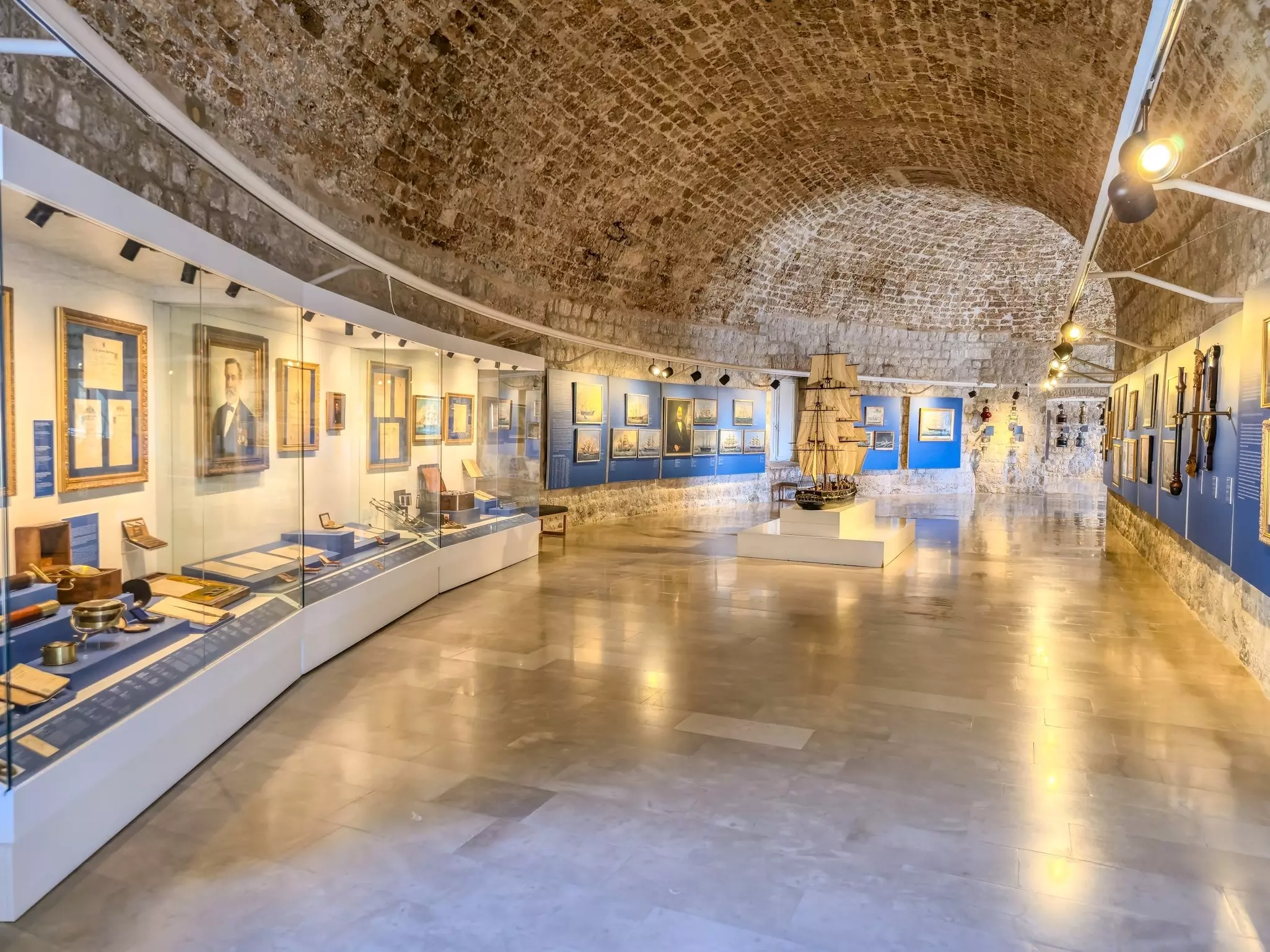 A museum exhibit with a naval theme including a model ship, artifacts and portraits.