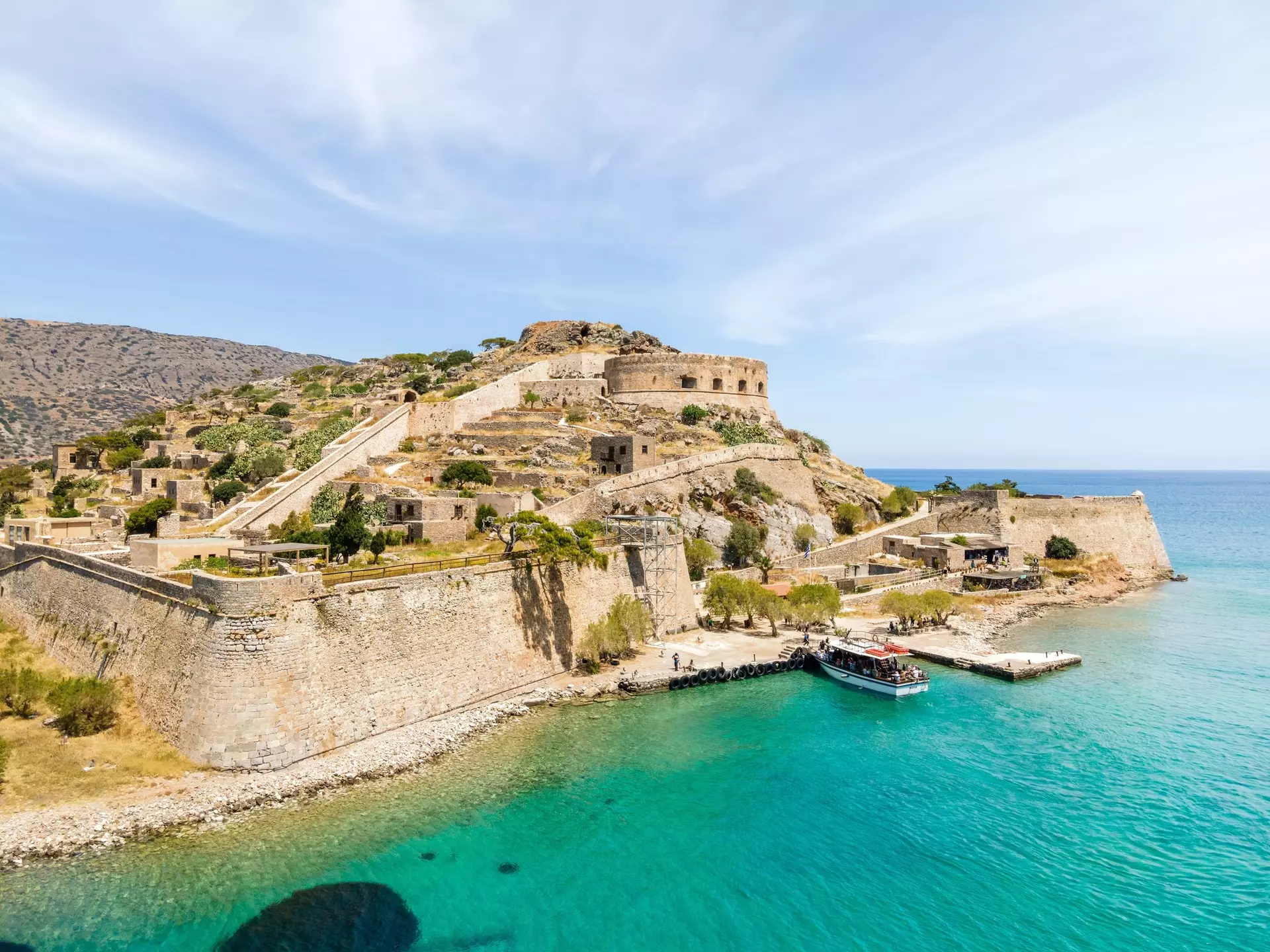 A boat of tourists docks at the beautiful Spinalonga island on Crete, Greece.