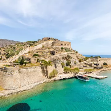 A boat of tourists docks at the beautiful Spinalonga island on Crete, Greece.