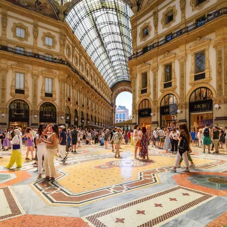 People stand inside an ornate shopping arcade in Milan. 
