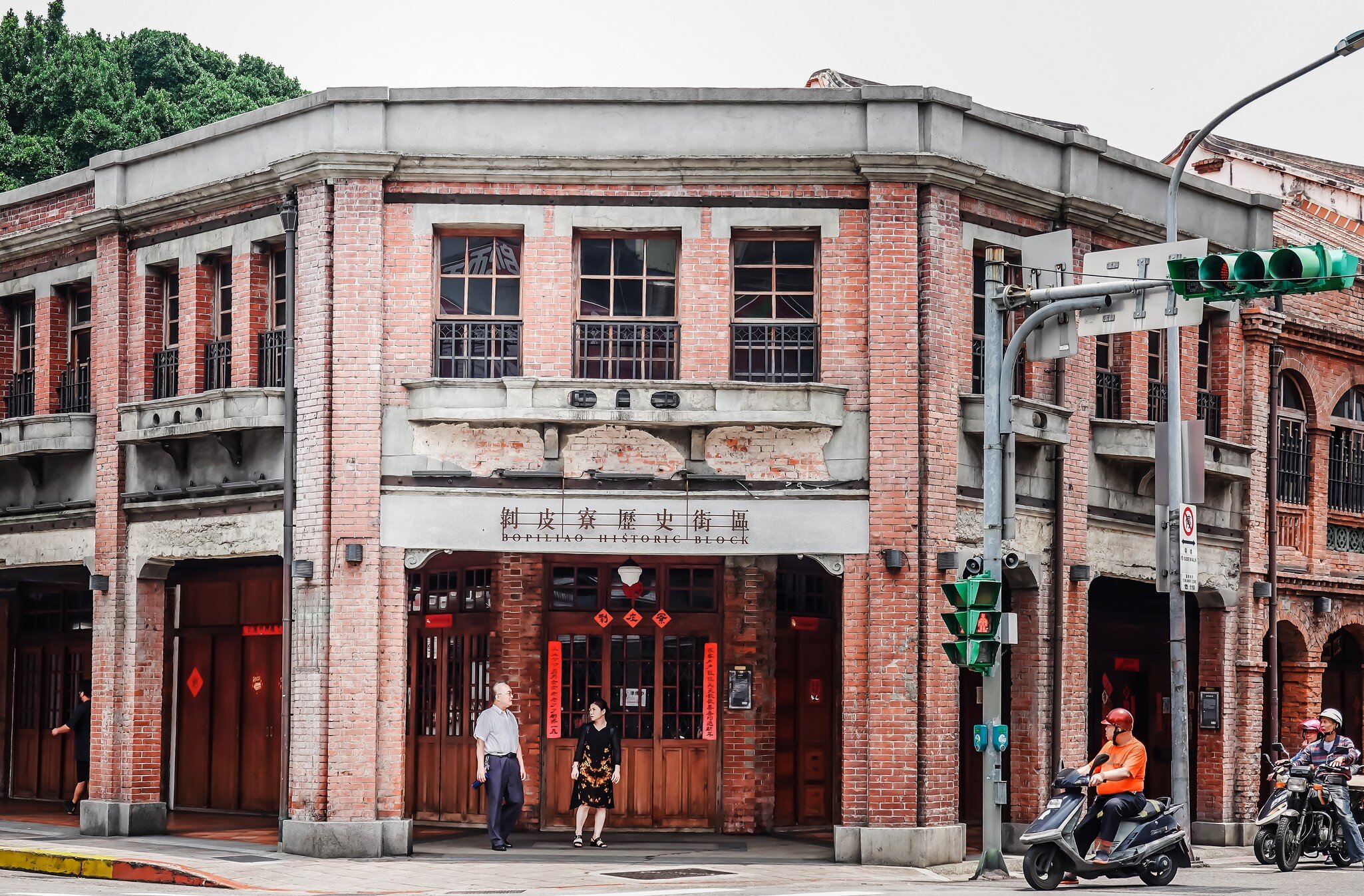 People stand at the brick facade entrance of Bopiliao Historical Block in Taipei, Taiwan.
