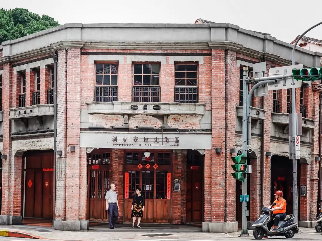 People stand at the brick facade entrance of Bopiliao Historical Block in Taipei, Taiwan.