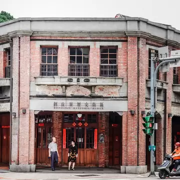 People stand at the brick facade entrance of Bopiliao Historical Block in Taipei, Taiwan.