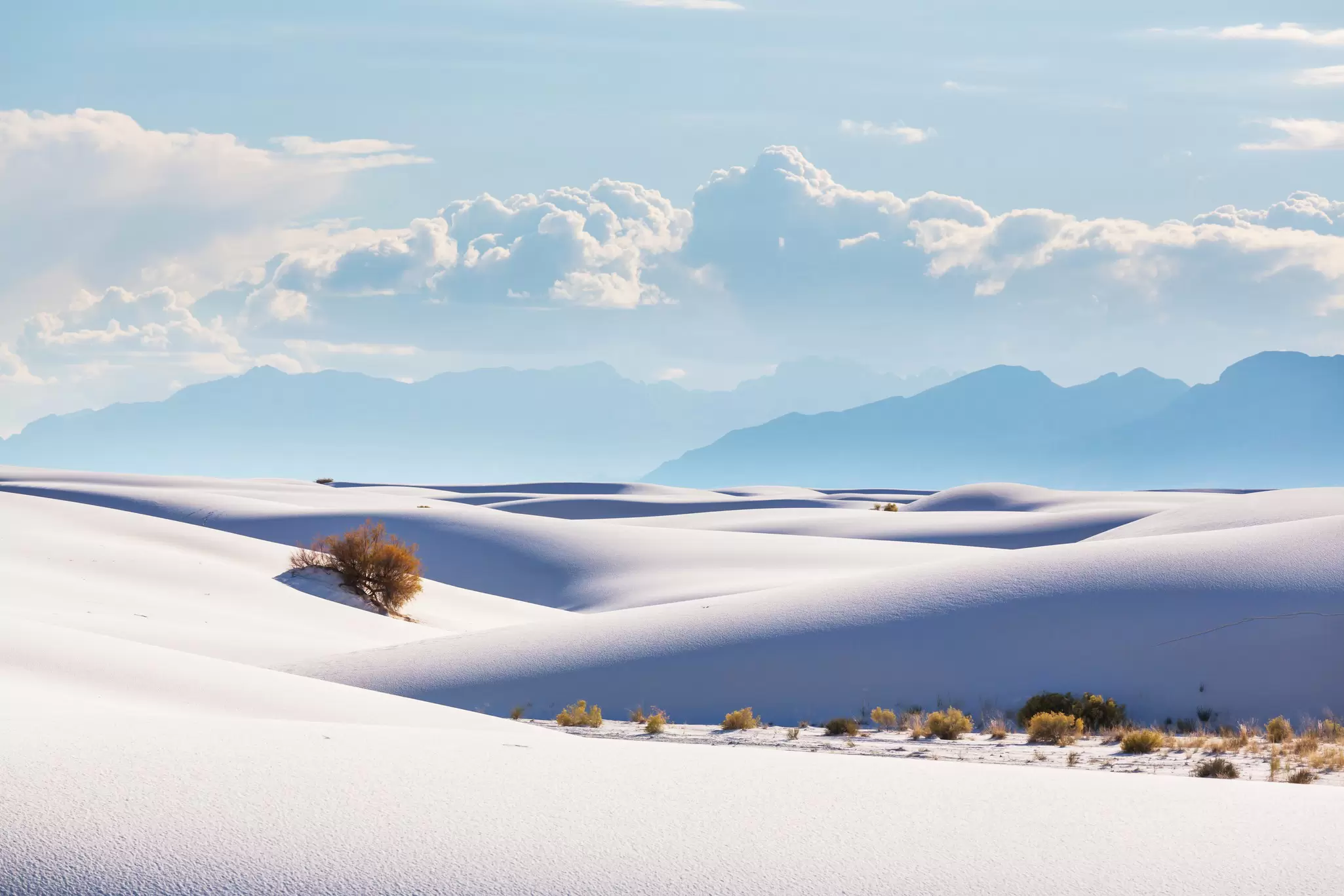 Unusual dunes with mountains and clouds in the background at White Sands National Park, New Mexico