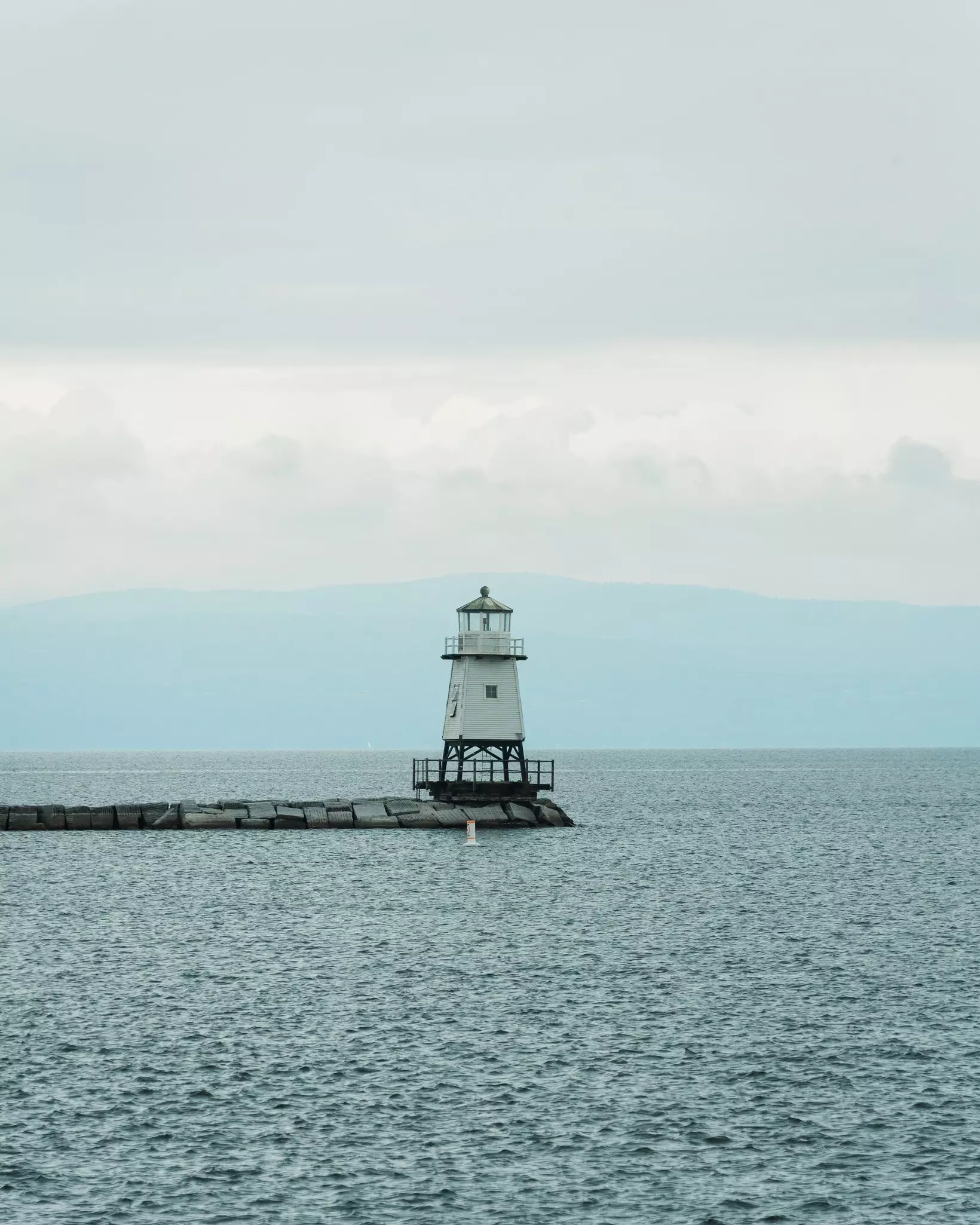 A small lighthouse at the end of a long pier