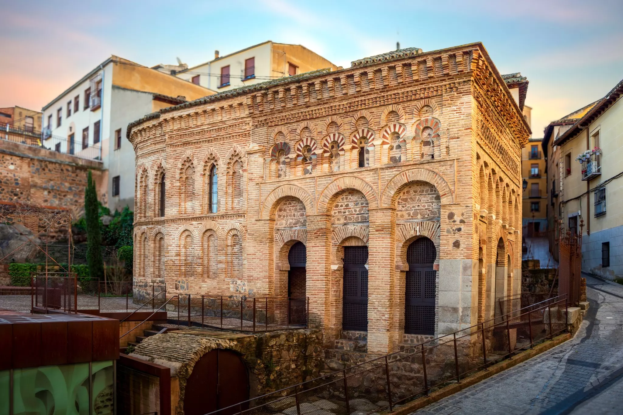 Exterior of an ancient brick mosque on the corner of a city street