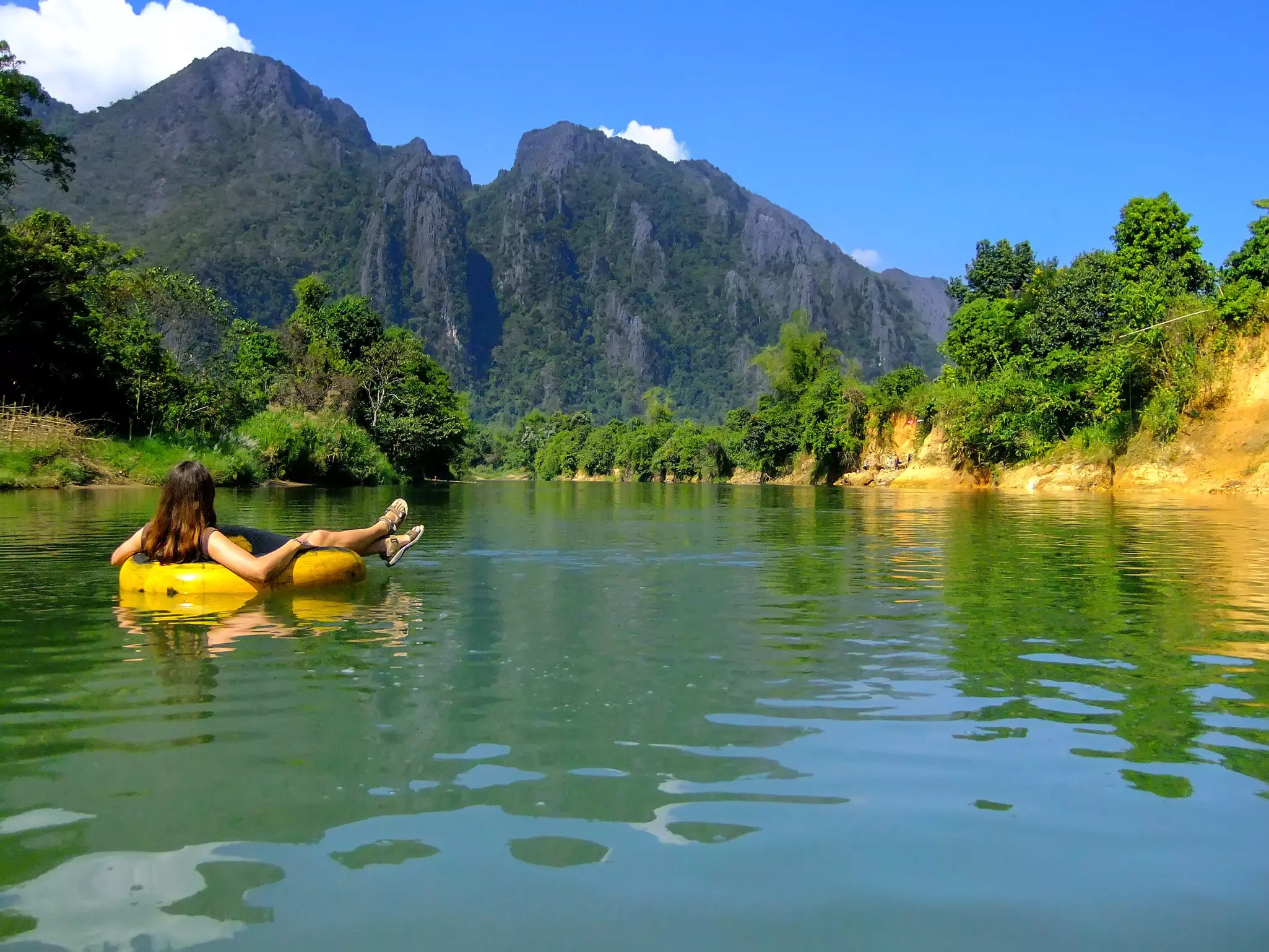 Tourist going down Nam Song River in a tube surrounded by karst scenery in Vang Vieng, Laos. 