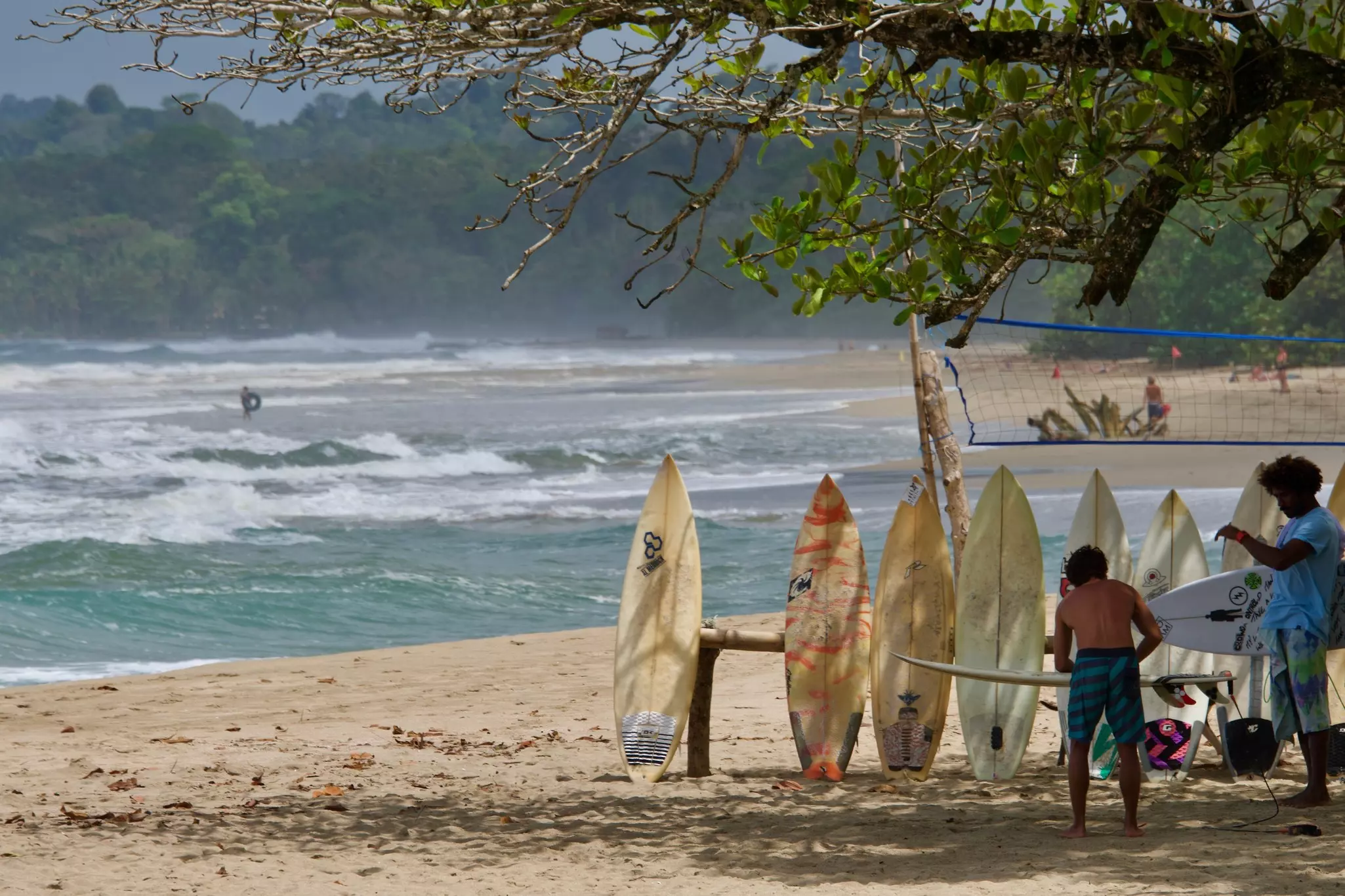 Some surfers and some boards lined up on the beach in Puerto Viejo, Talamanca Costa Rica with some strong surf in the background. 