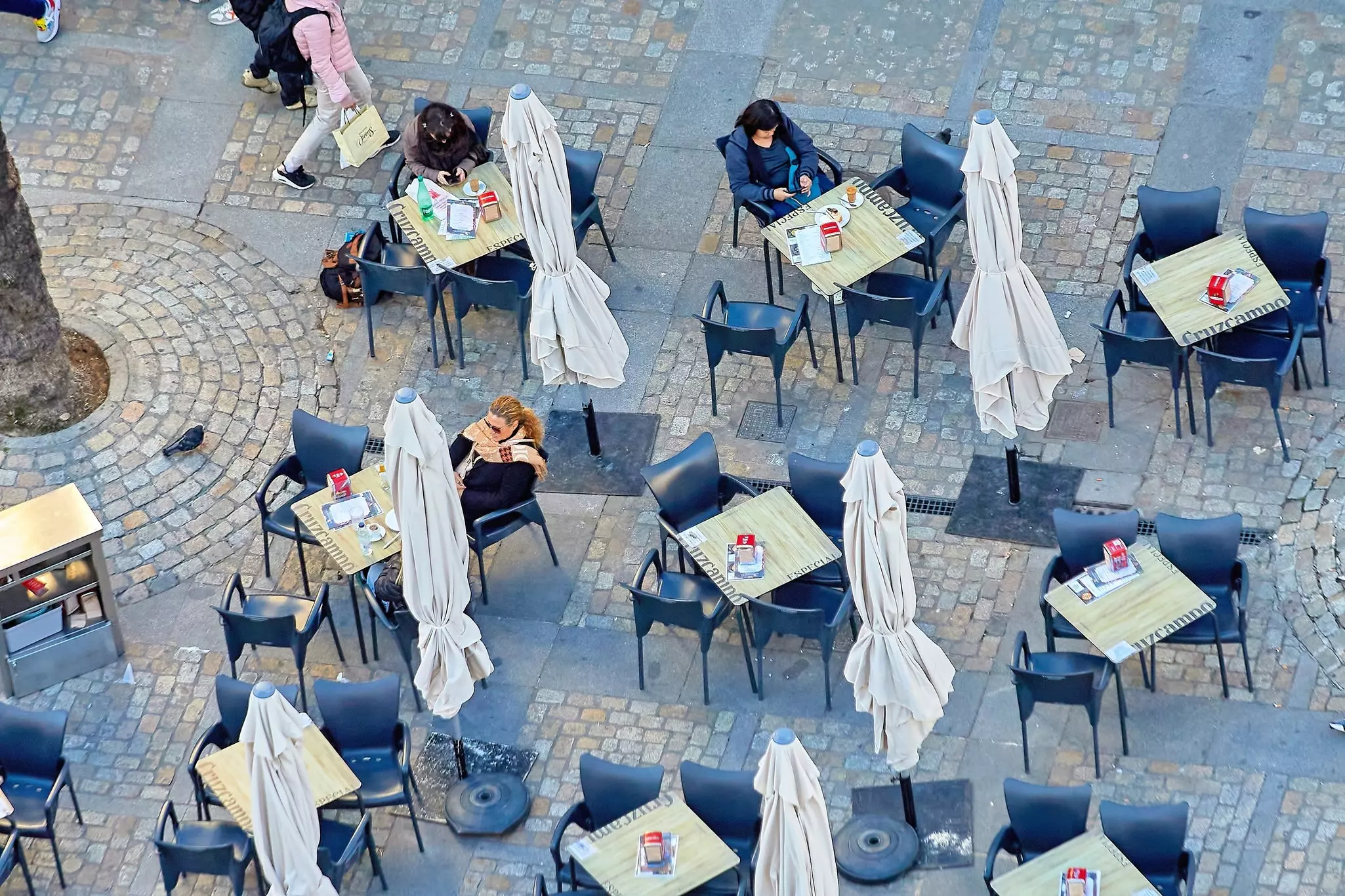 Tables, chairs and umbrellas of a cafe in a city square.
