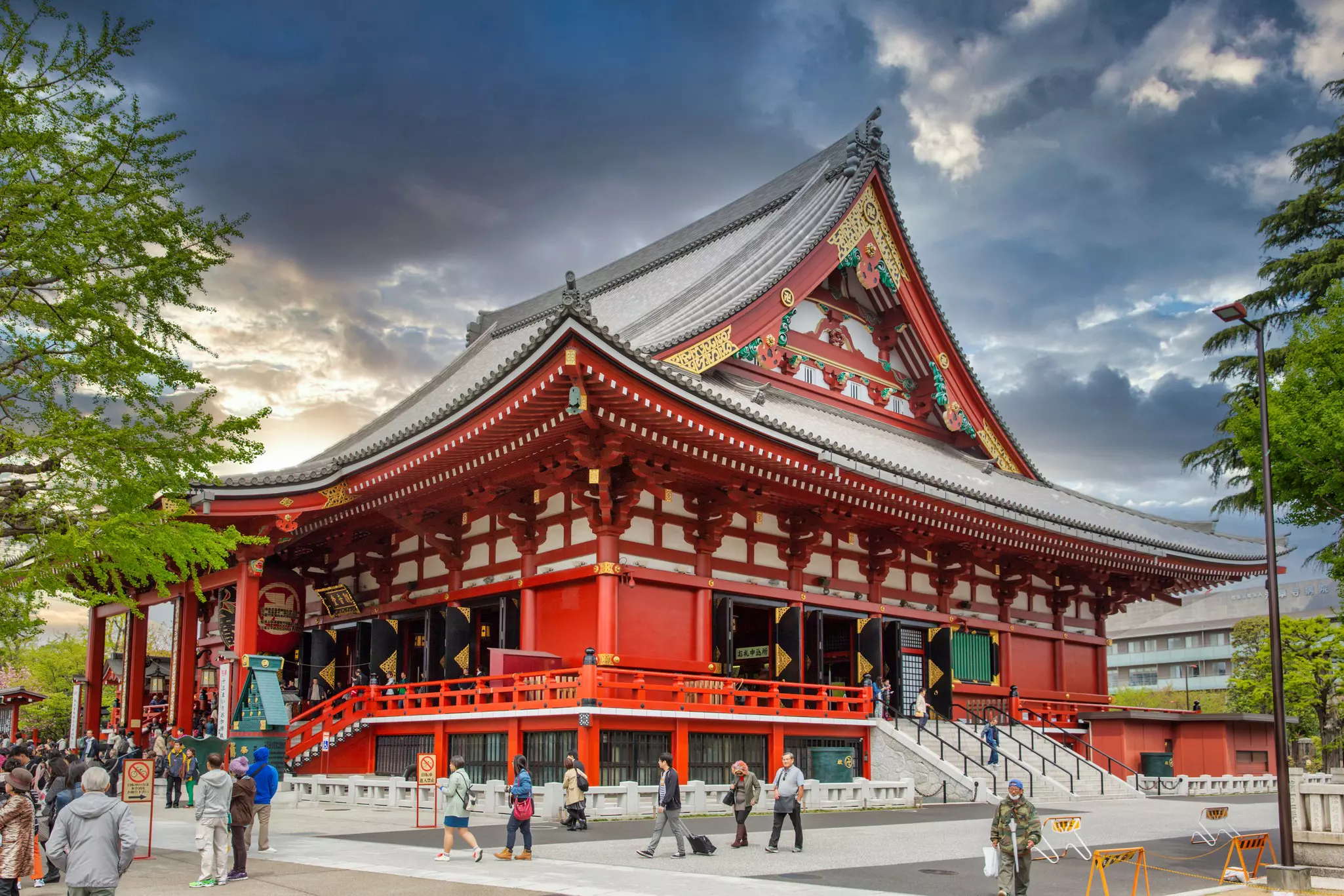 Visitors walk by a large red Buddhist temple