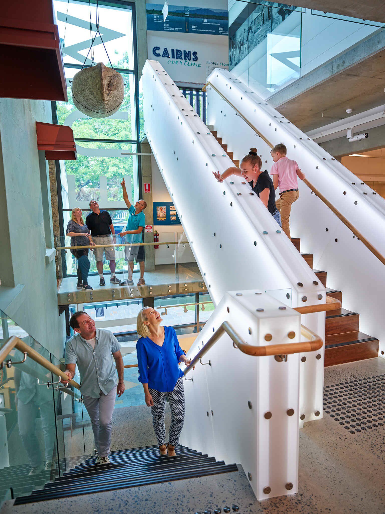 Interior of Cairns museum, with families and children walking up the steps. Cairns, Australia.