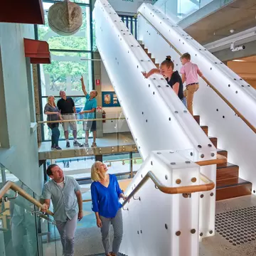 Interior of Cairns museum, with families and children walking up the steps. Cairns, Australia.