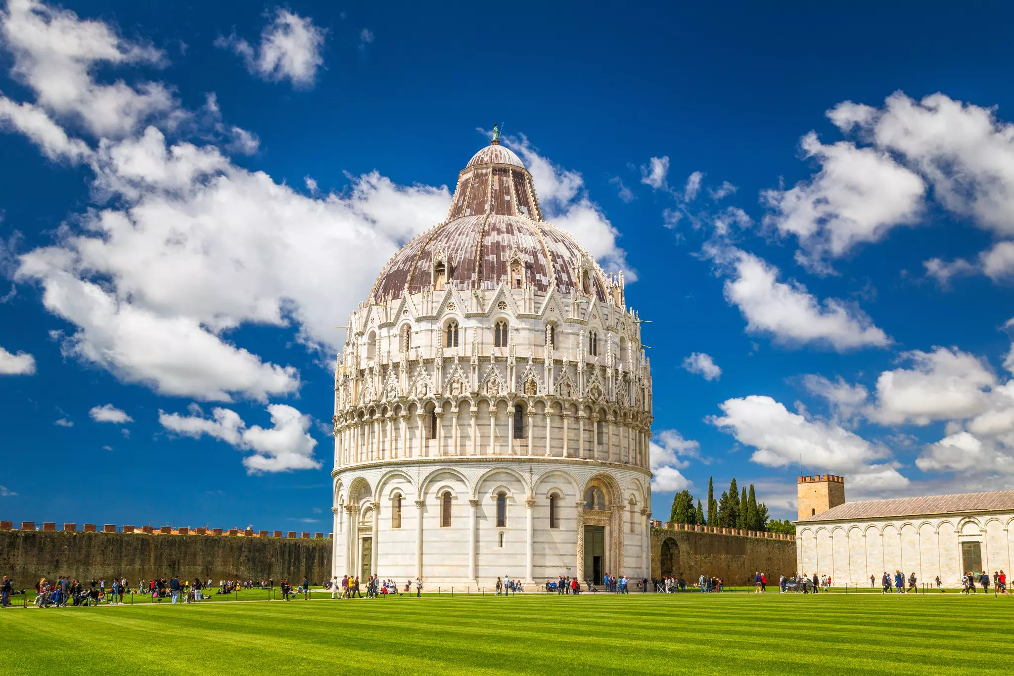 A round white marble building with a dome roof in the center of a green lawn.