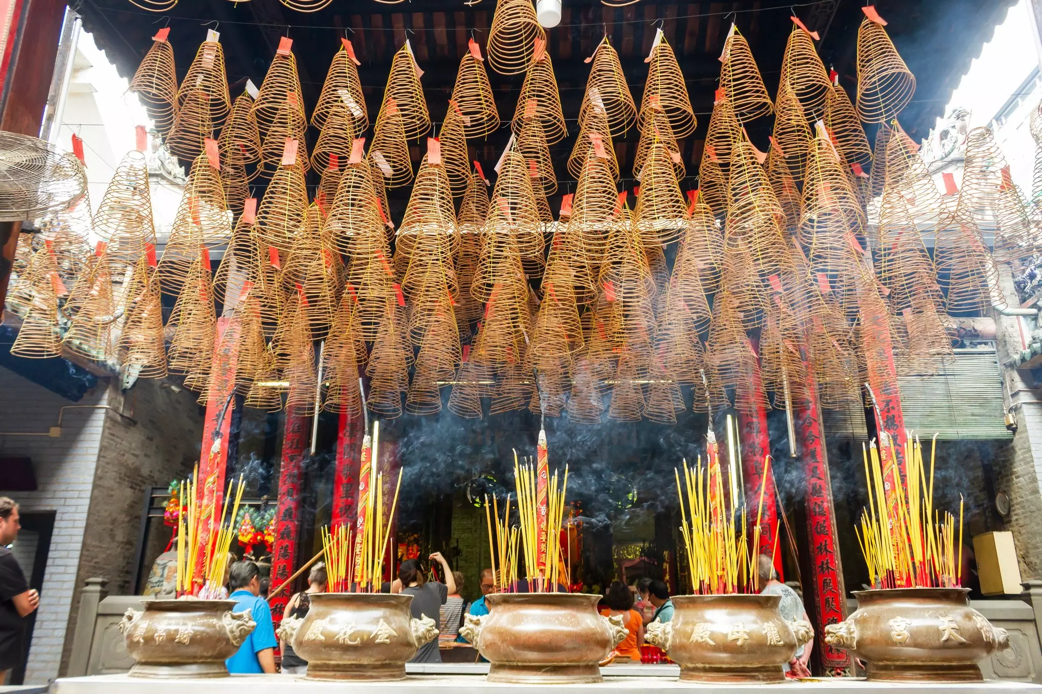 Five vessels with burning incense sticks are lined up at a temple in Vietnam.