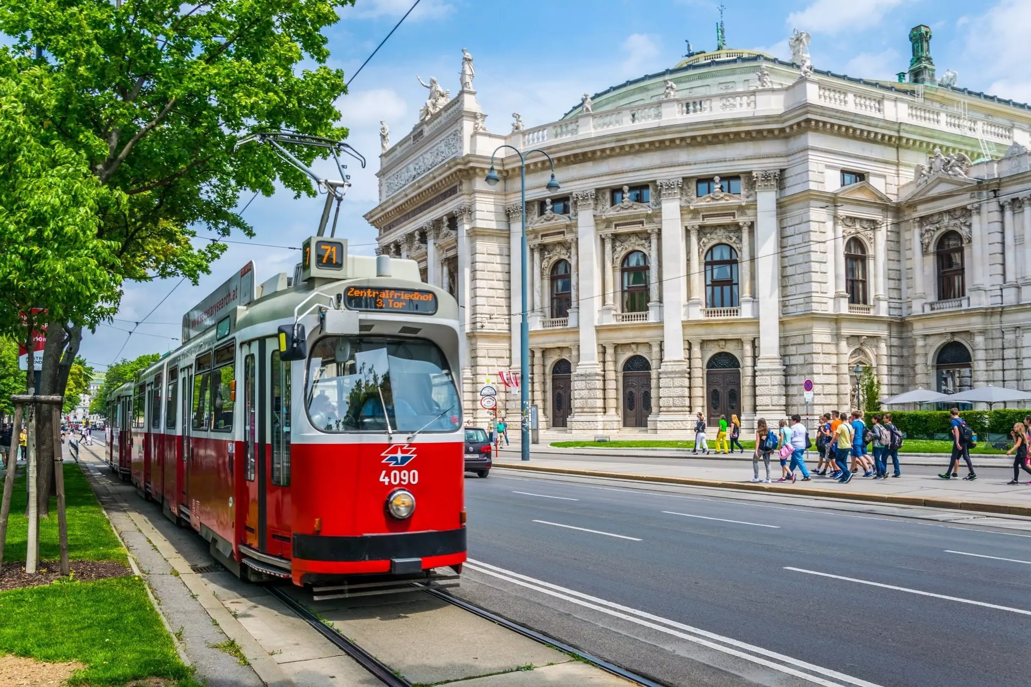Visitors walk along Vienna's Ringstrasse, past the historic Burgtheater