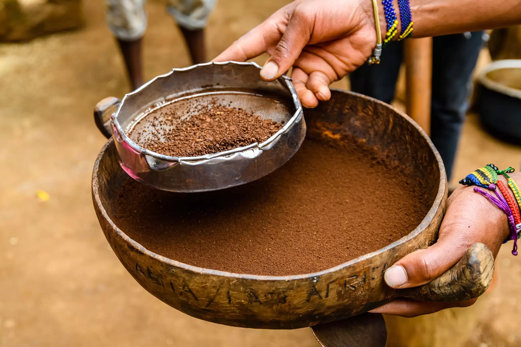 A close-up shot of a person sifting coffee grounds in a village.