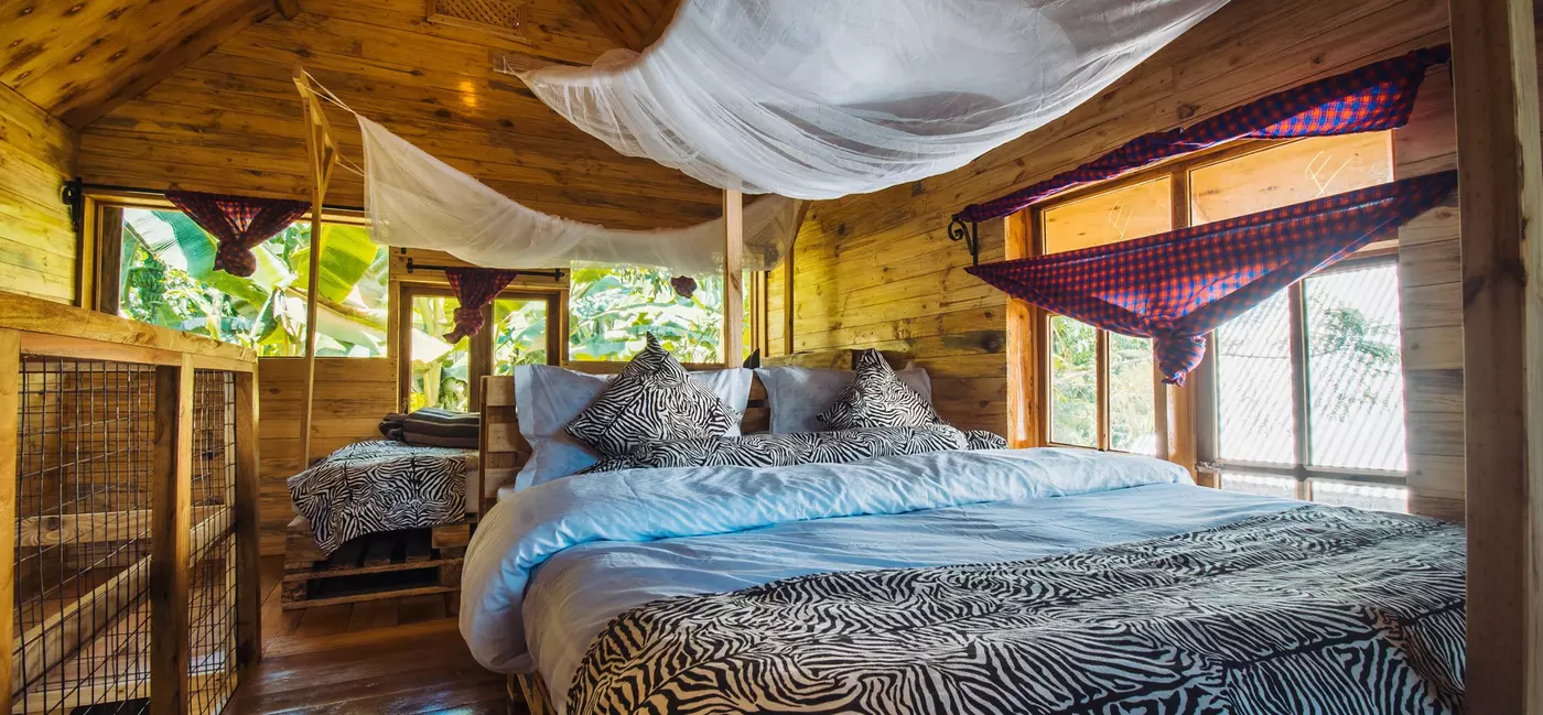 A double bed with mosquito nets within a wooden cabin.