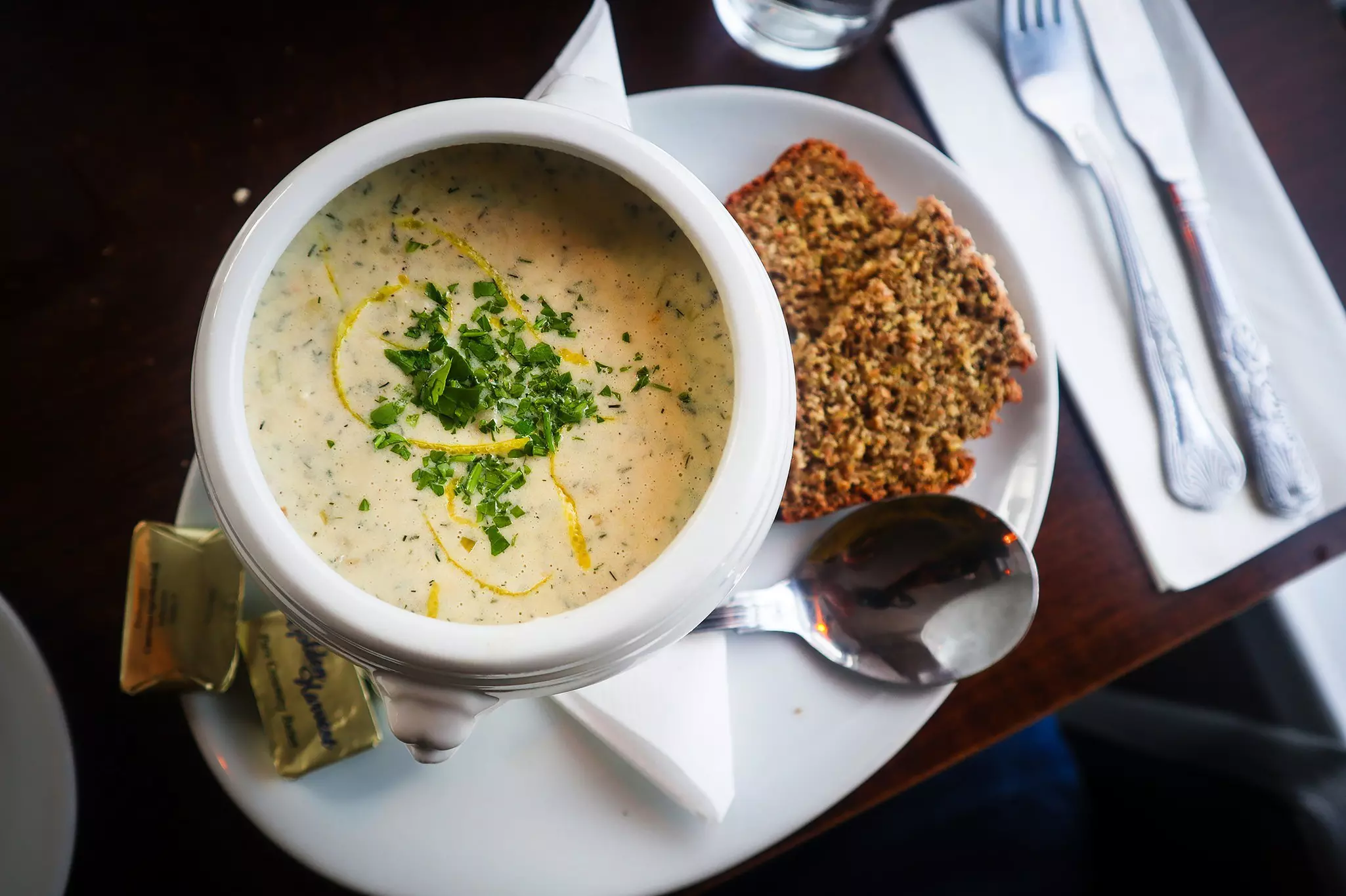 A bowl of creamy soup with slices of dark bread.