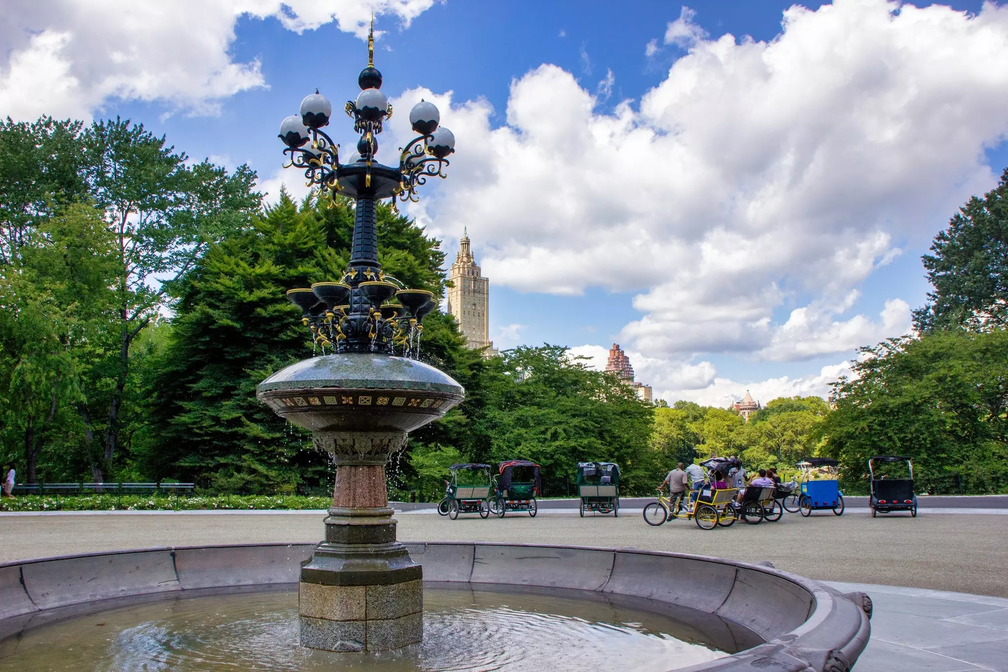Where Victorian carriages once gathered, pedicabs wait for customers at the Cherry Hill Fountain in Central Park. San Remo Apartments is in the background. 