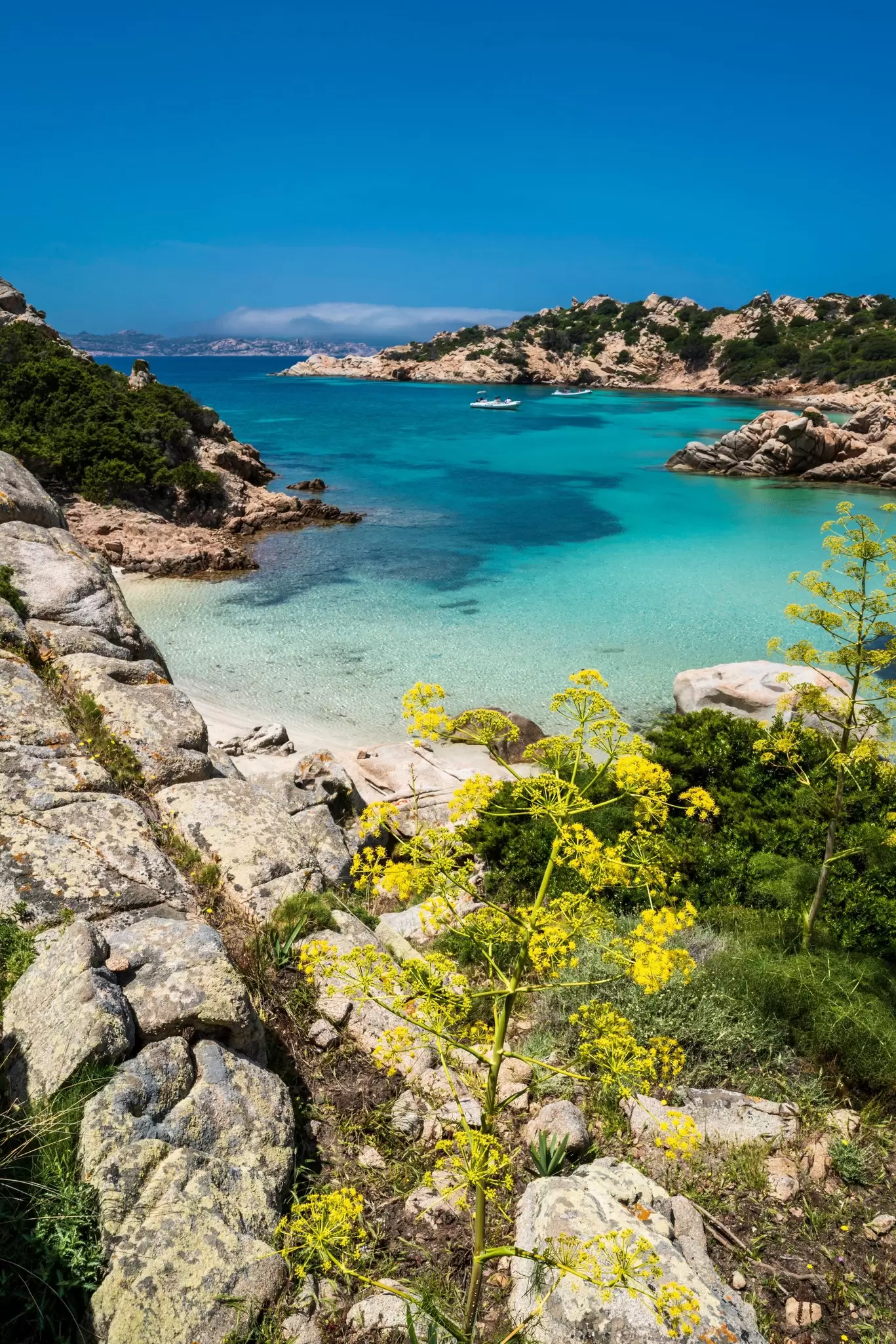 A small, isolated cove below a rocky cliff has white sand and turquoise water.