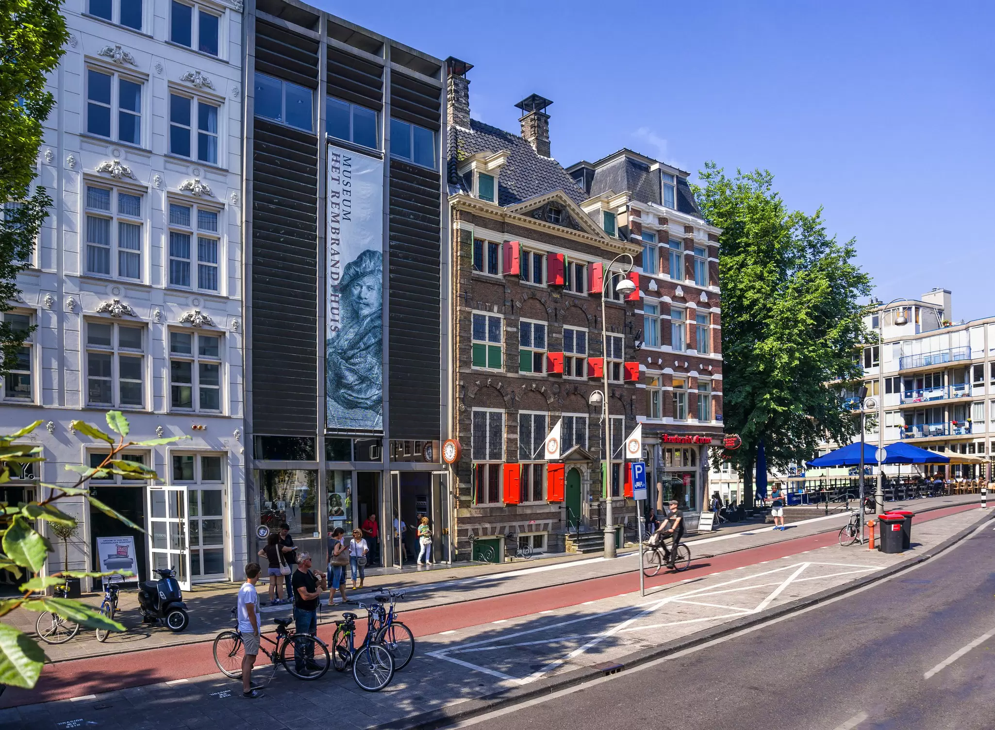 The exterior of the Museum het Rembrandthuis in Amsterdam on a sunny day with people mingling outside