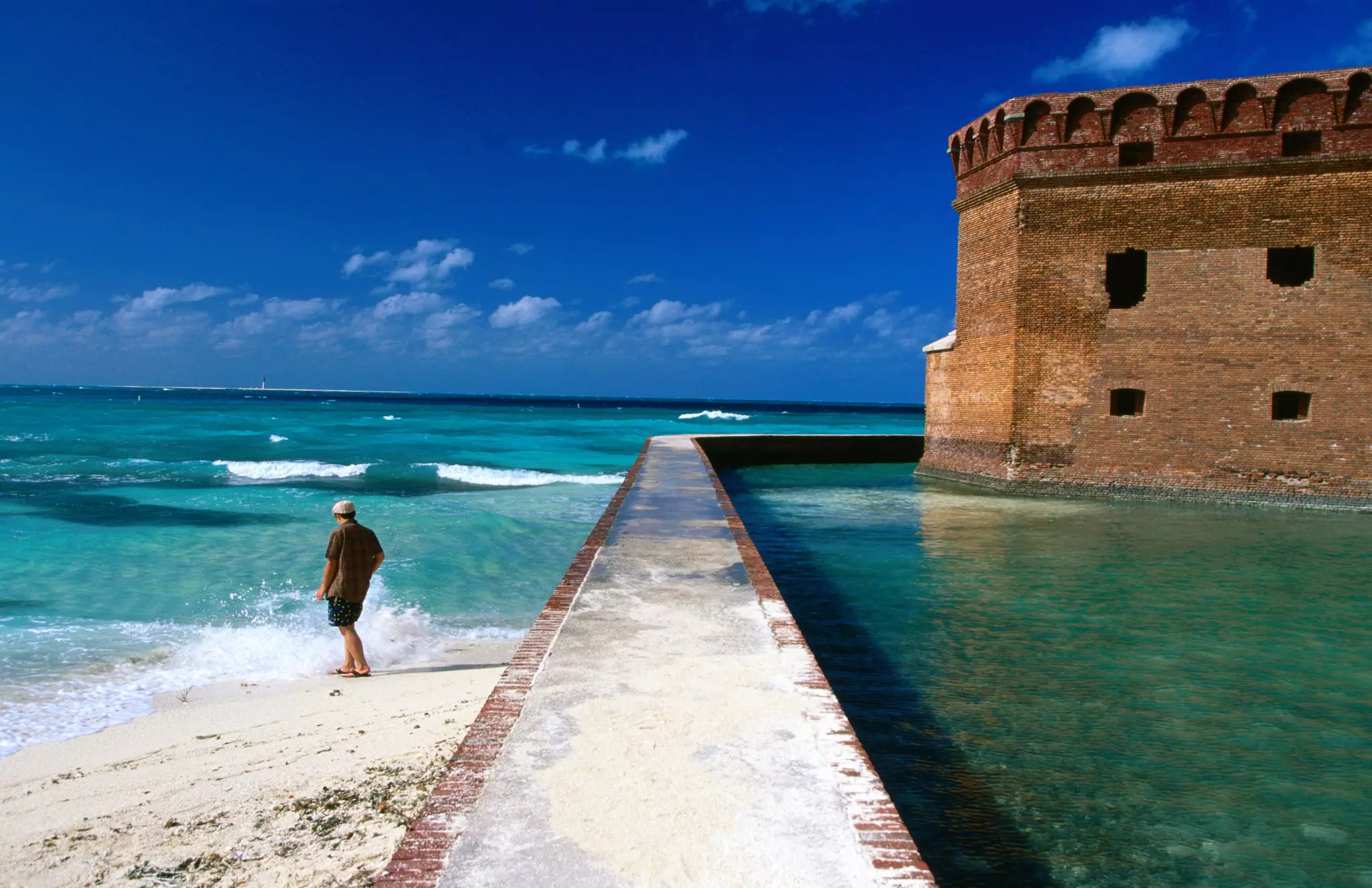 A man walks in the surf by the fort at Dry Tortugas National Parl, Florida.
