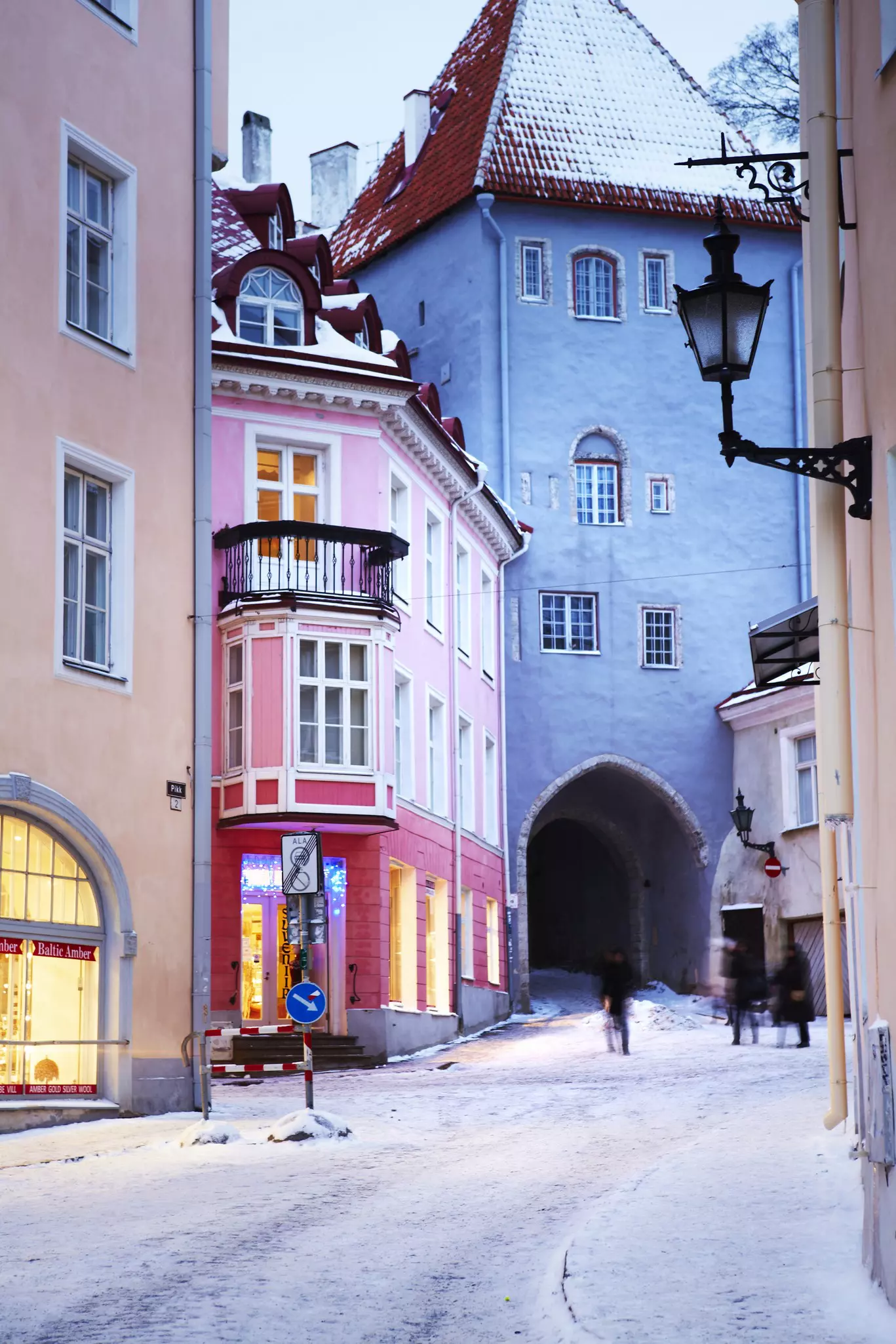 Pink and blue facades of European style buildings with snow on the ground and an arched tunnel