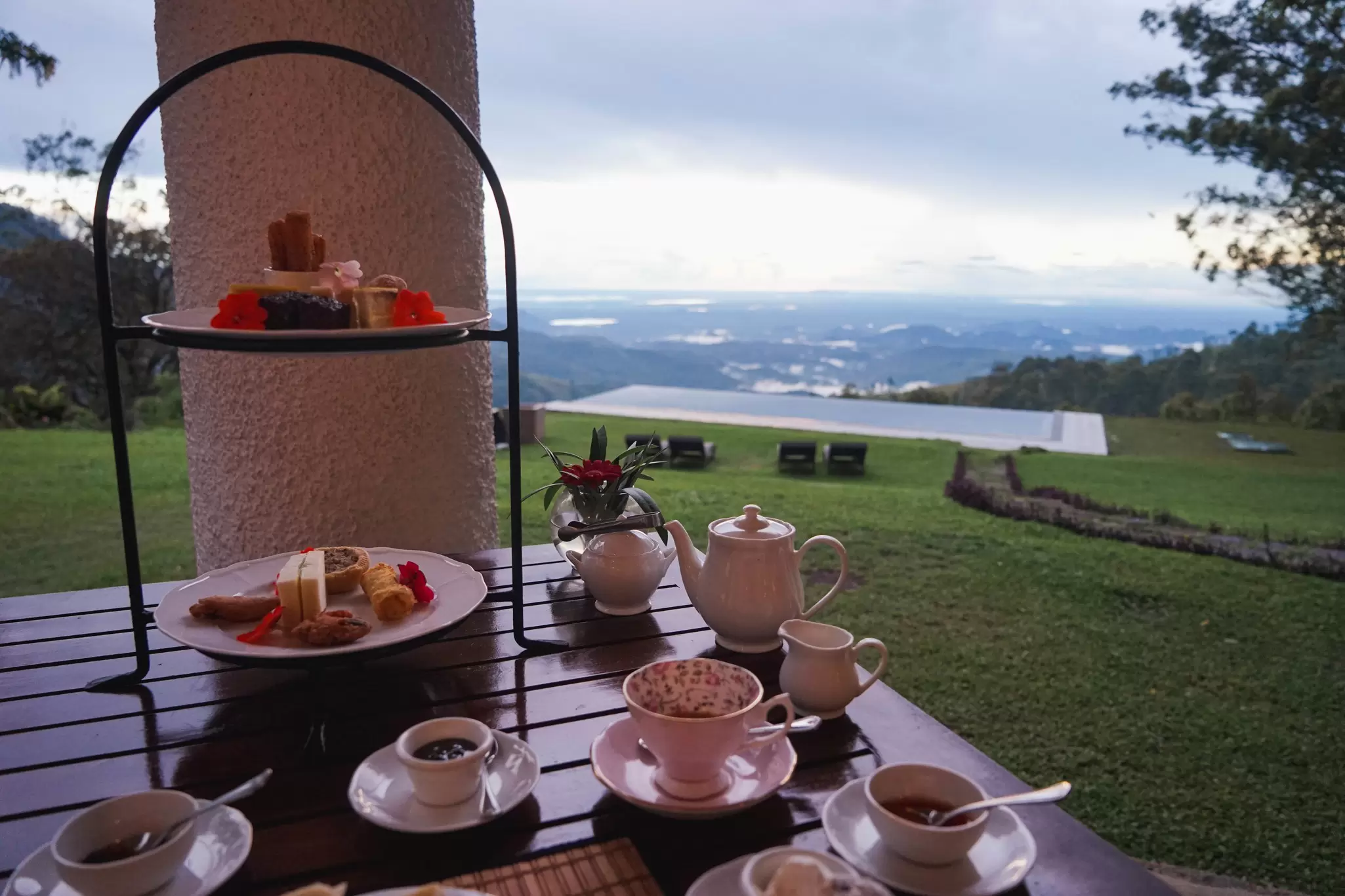 Tea and small snacks on a table with a lawn and swimming pool in the background: tea at Thotalagala hotel in Haputale, Sri Lanka
