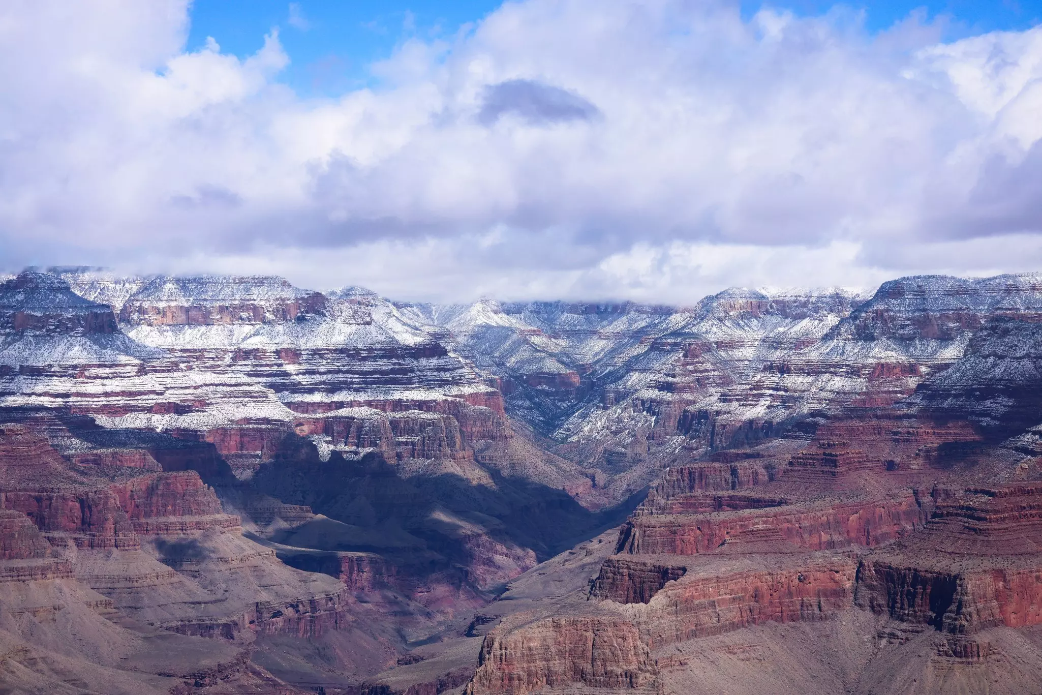 Red rocks in a large canyon covered with a light dusting of snow.